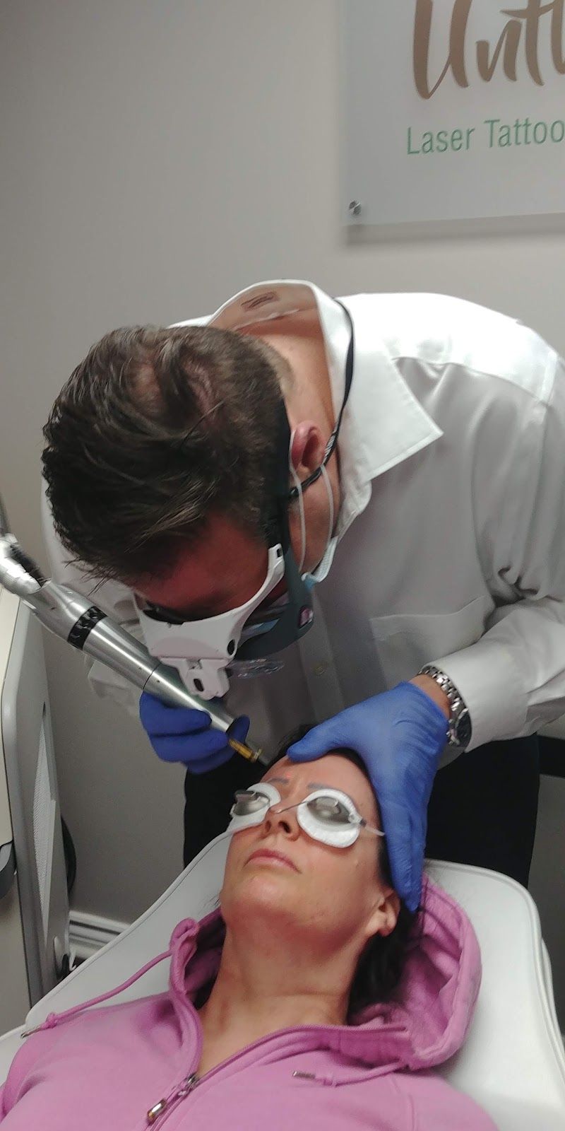 Dentist examining a patient’s teeth with a dental mirror while she reclines in a chair