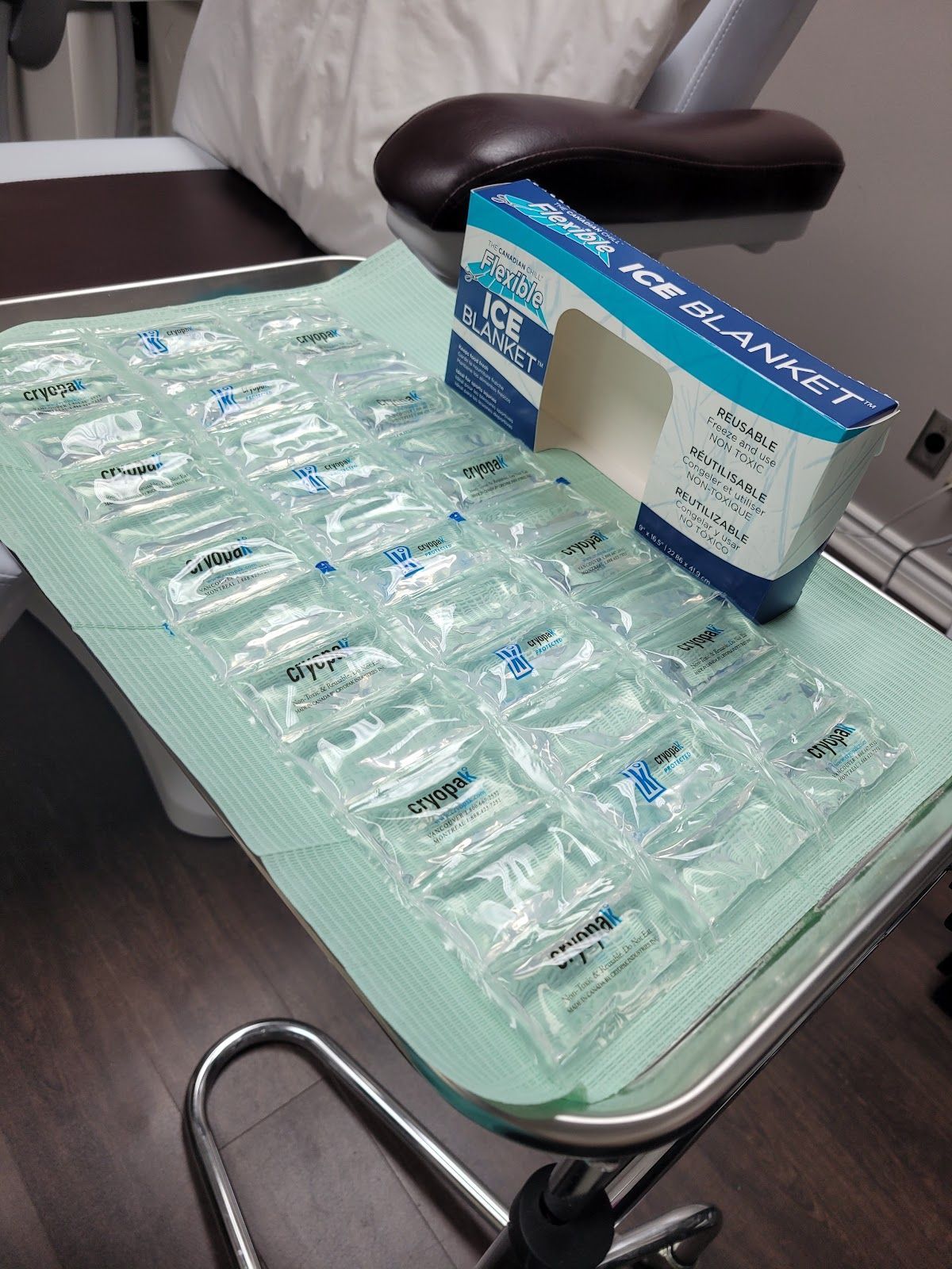 Dental tray with rows of clear plastic dental aligners and a blue-and-white aligner box on a chair