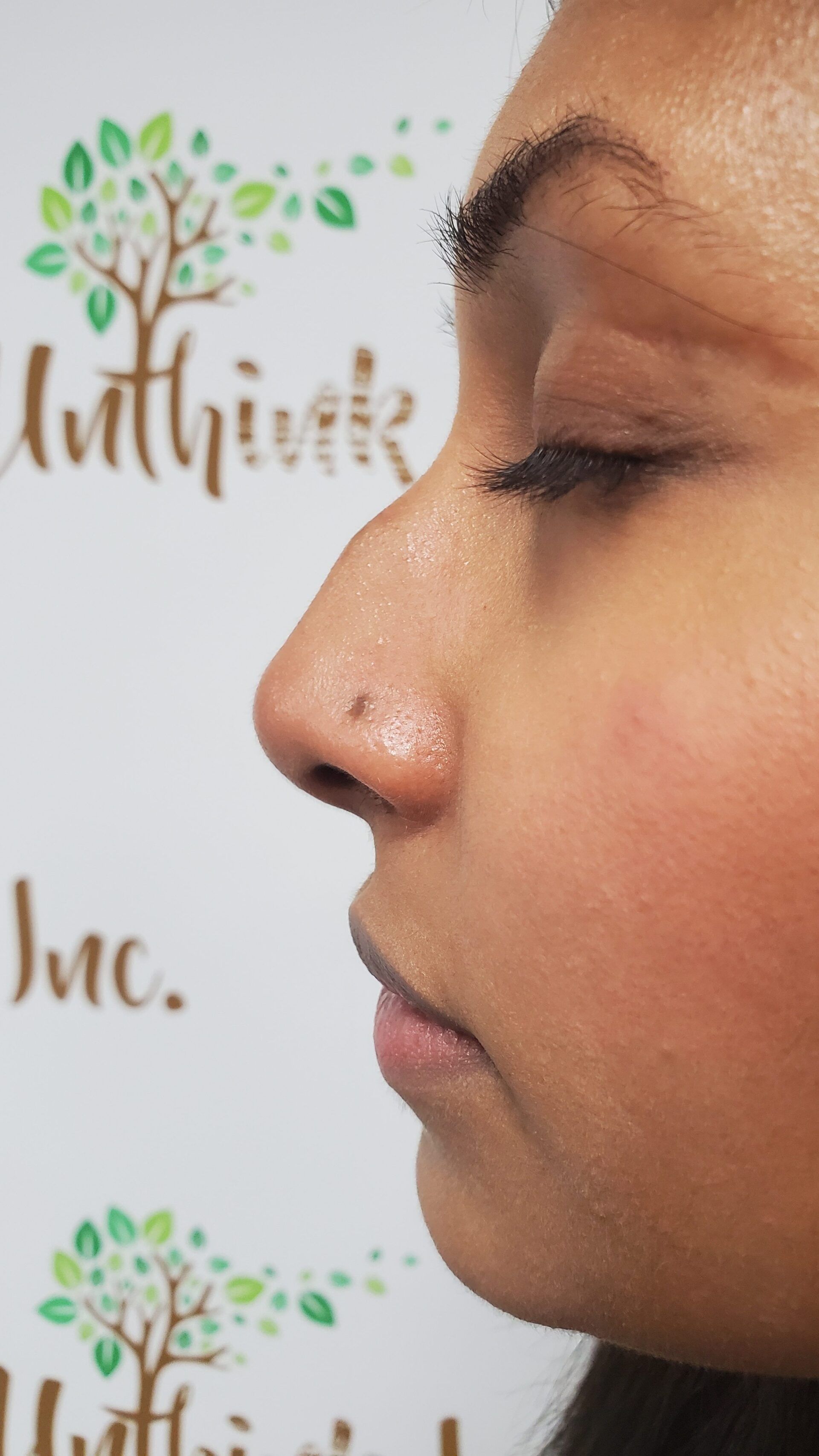 A close up of a woman 's nose with a tree in the background