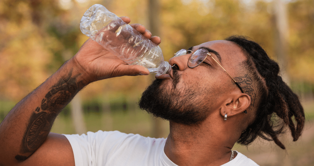 A man is drinking water from a plastic bottle.