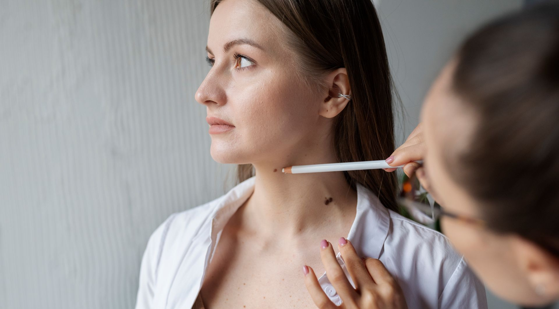 Doctor checking a woman’s neck with a thermometer in a clinic