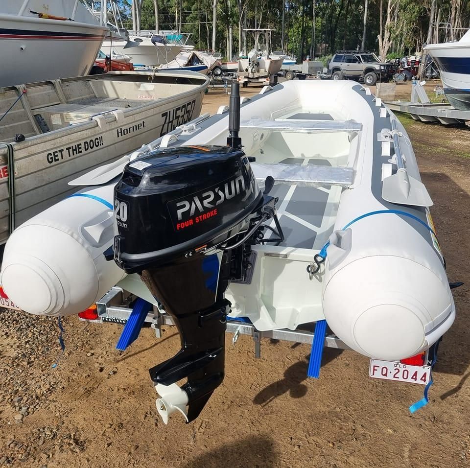 A row of outboard motors are lined up on the shore of a lake.