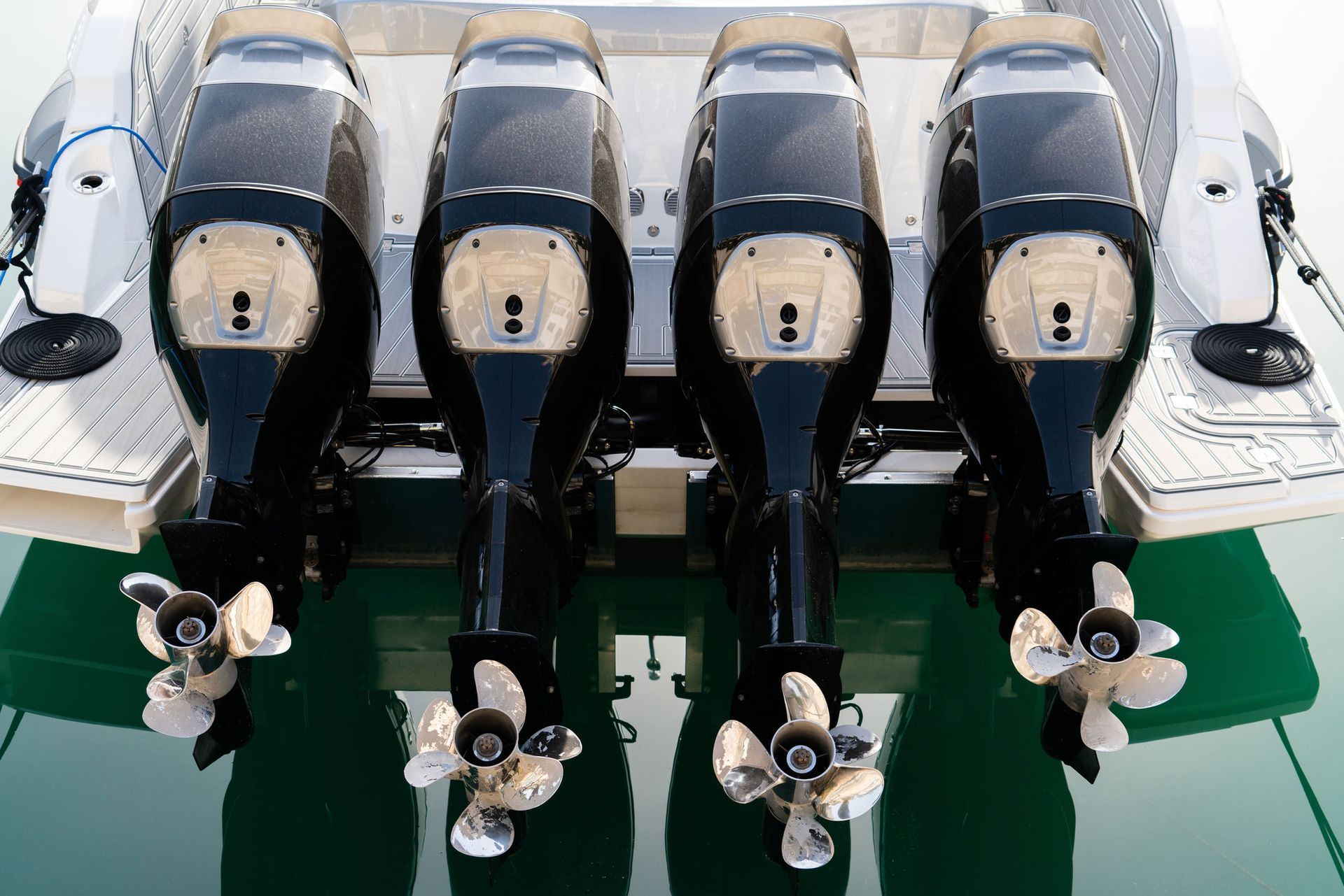 A row of outboard motors are lined up on the shore of a lake.