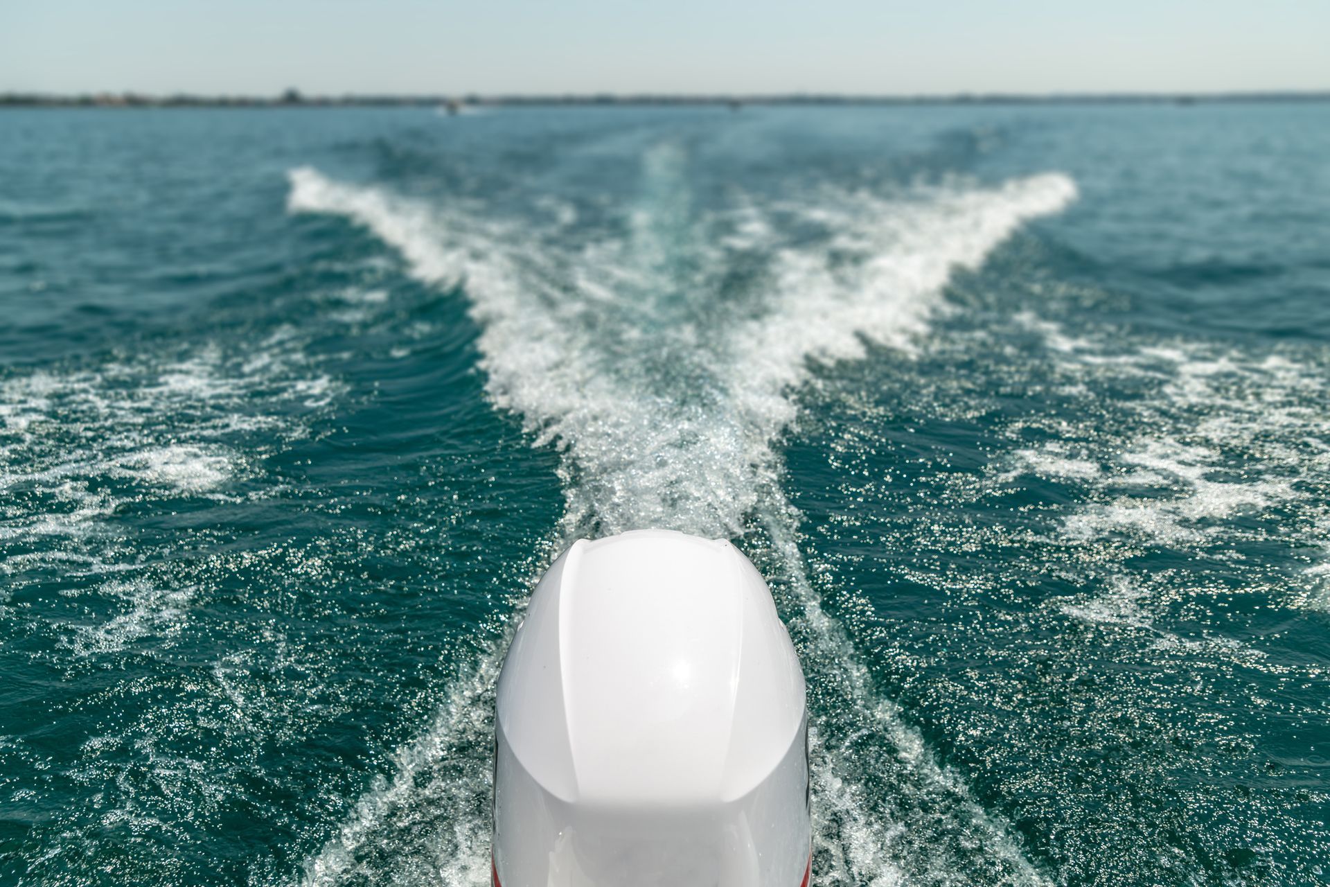 The engine of a boat is sitting in front of a thatched hut.