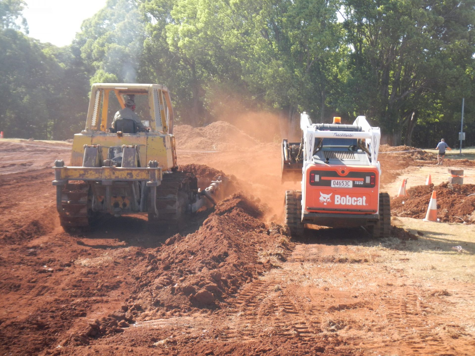 Bulldozer and Bobcat Excavating Dirt at A Construction Site — Evans Earthmoving Contractors In Malanda, QLD 