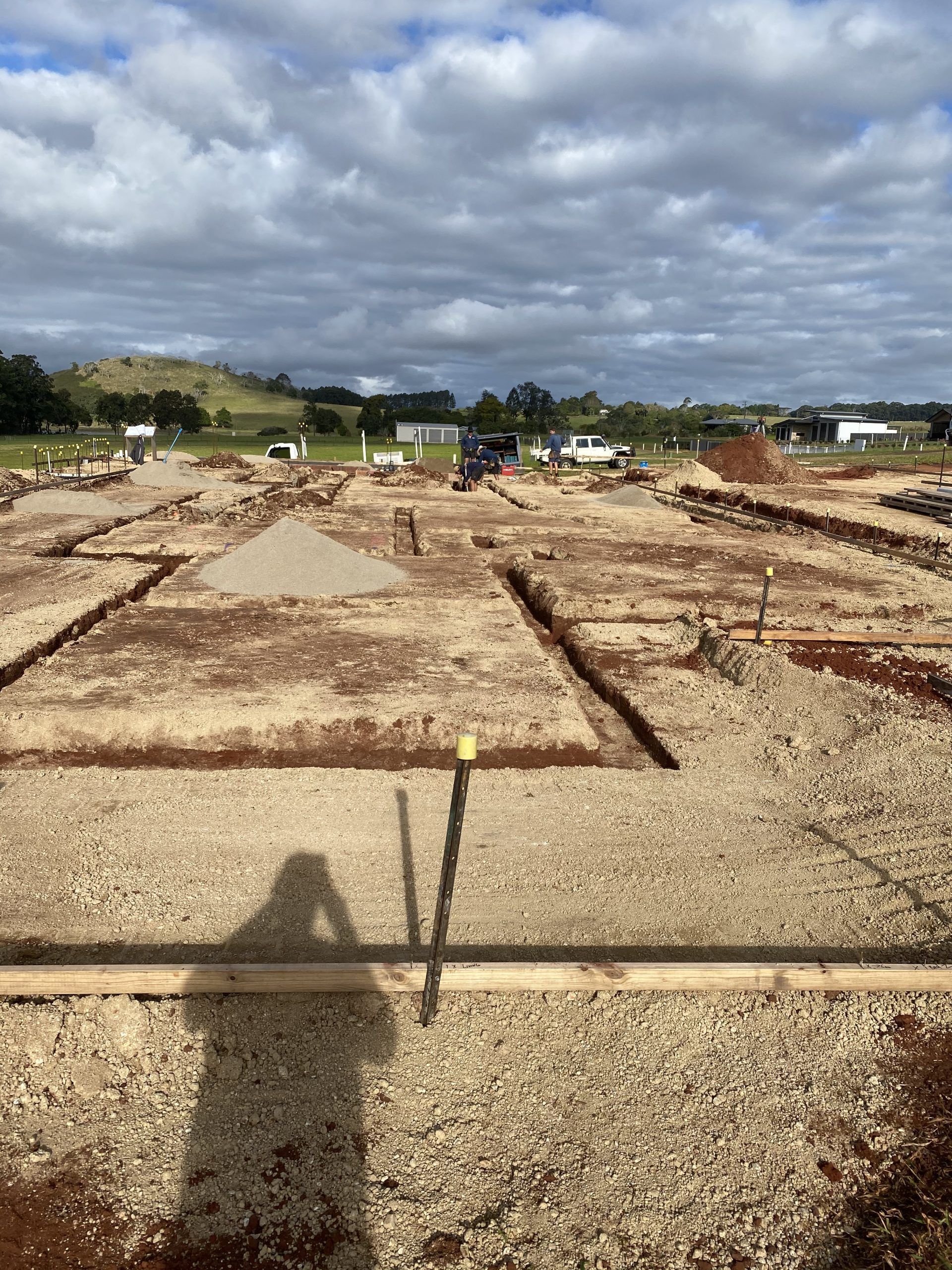Dirt construction site with trenches and gravel under a cloudy sky, viewed across a flat open field — Evans Earthmoving Contractors In Malanda, QLD 