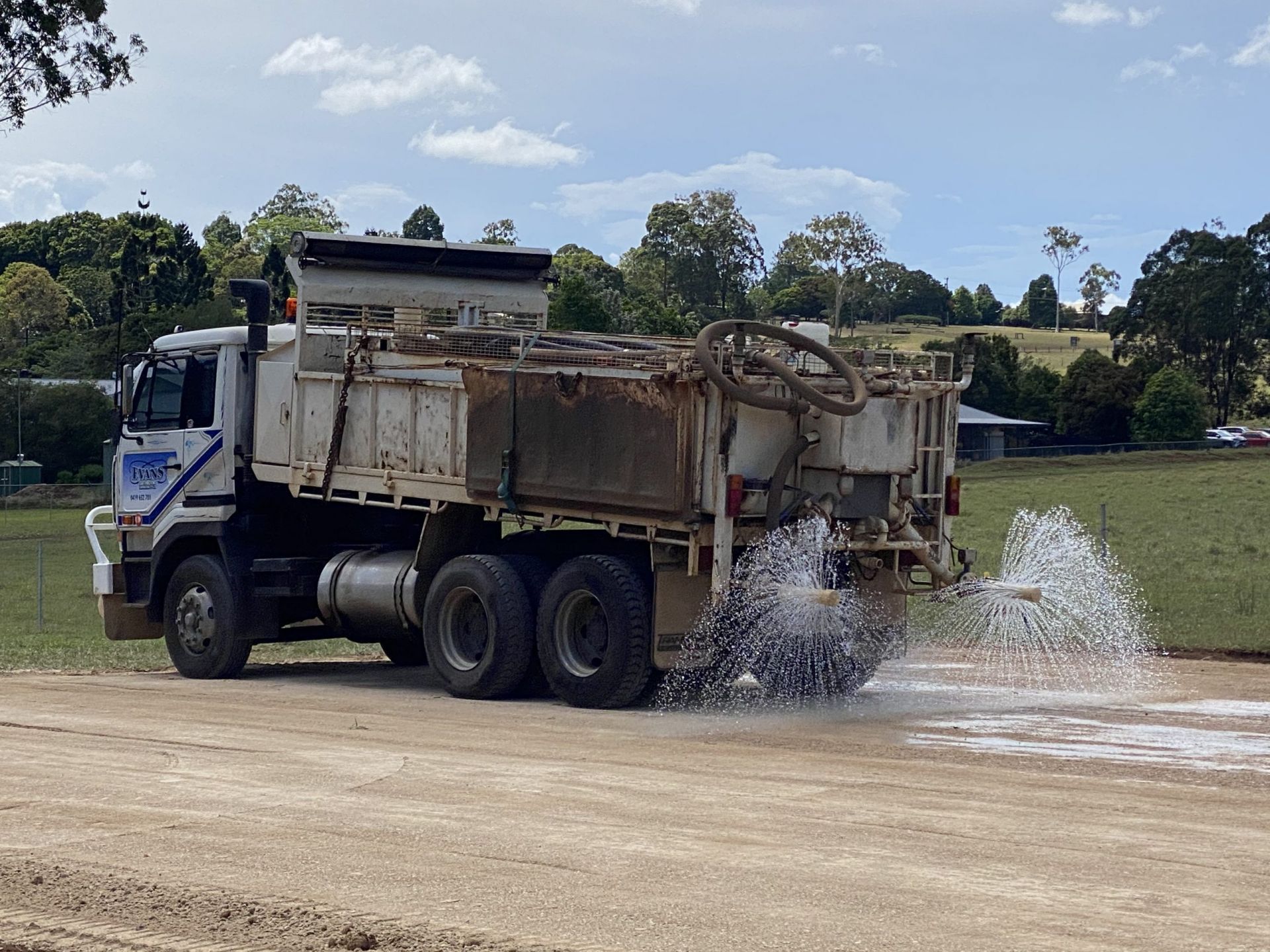 Water Truck Spraying Water on A Dirt Road — Evans Earthmoving Contractors In Malanda, QLD 