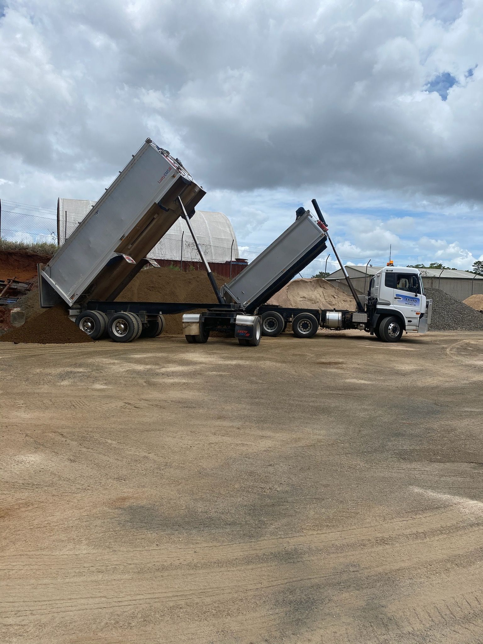 Dump Truck Unloading Gravel at A Construction Site Under a Cloudy Sky — Evans Earthmoving Contractors In Malanda, QLD 