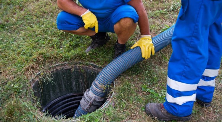 Workers in Blue Suits and Yellow Gloves Pumping a Septic Tank — Evans Earthmoving Contractors In Malanda, QLD 