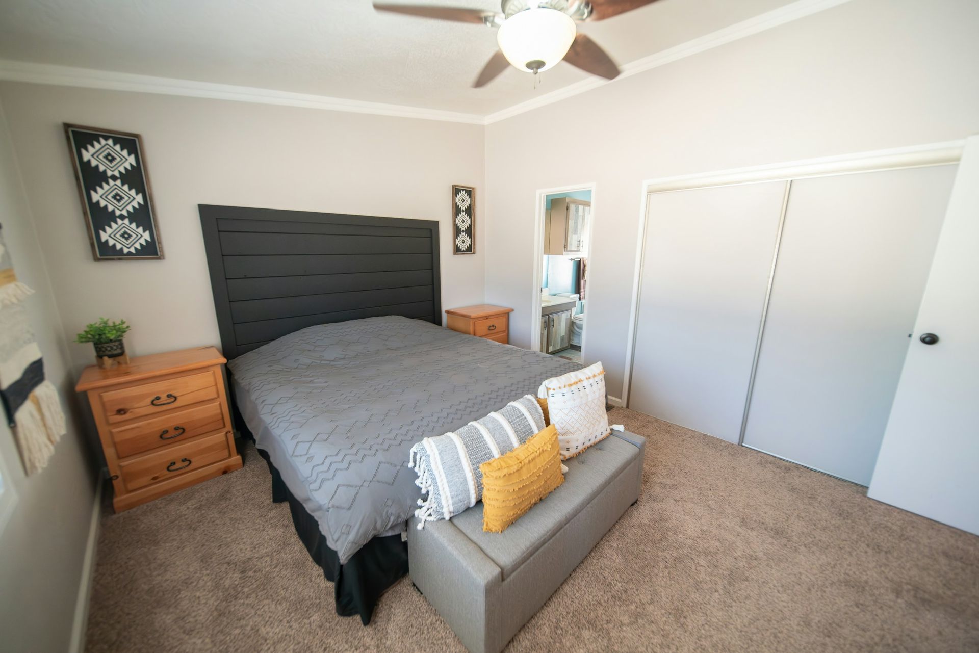 A bedroom with a bed , nightstand , dresser and ceiling fan.