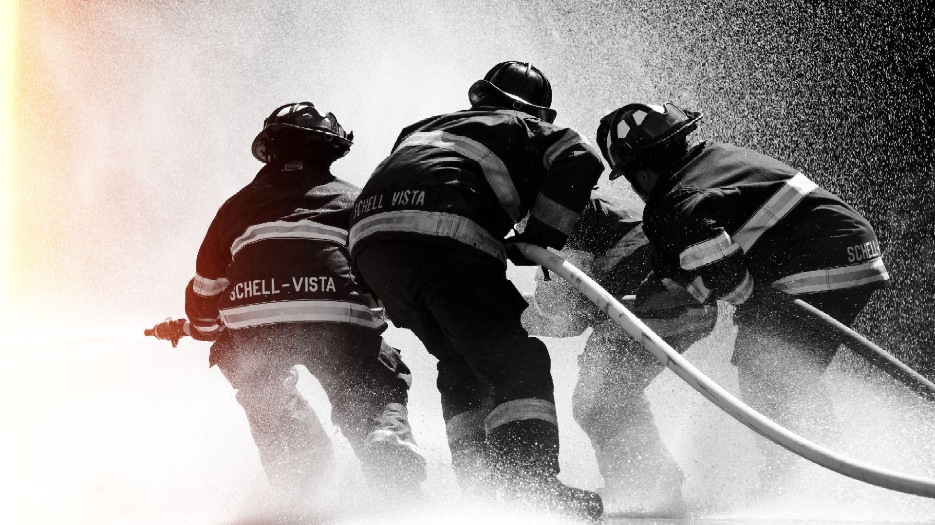 A group of firefighters are spraying water on a fire