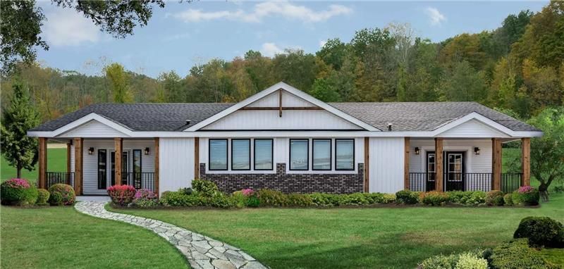 Modern manufactured home with white exterior, brick accents, front porch columns, and landscaped yard in a rural setting
