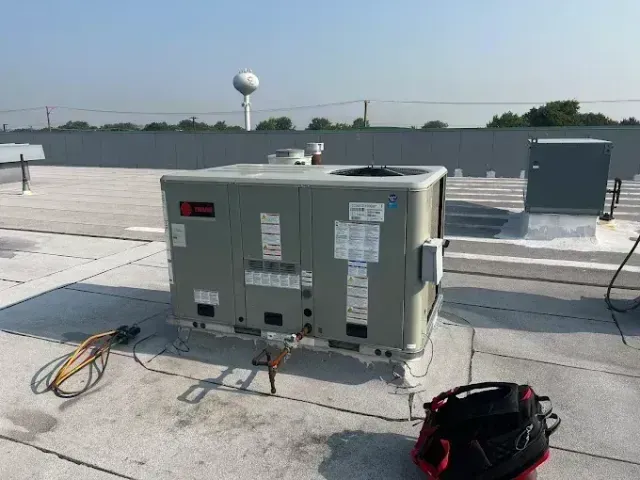 HVAC unit on a flat rooftop with cables and equipment nearby under a clear sky