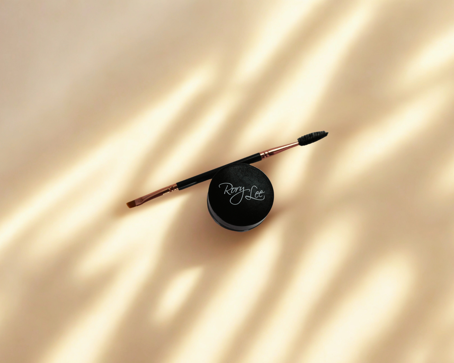 A RoryLee® Makeup lipstick and a lip pencil are sitting on a wooden table.