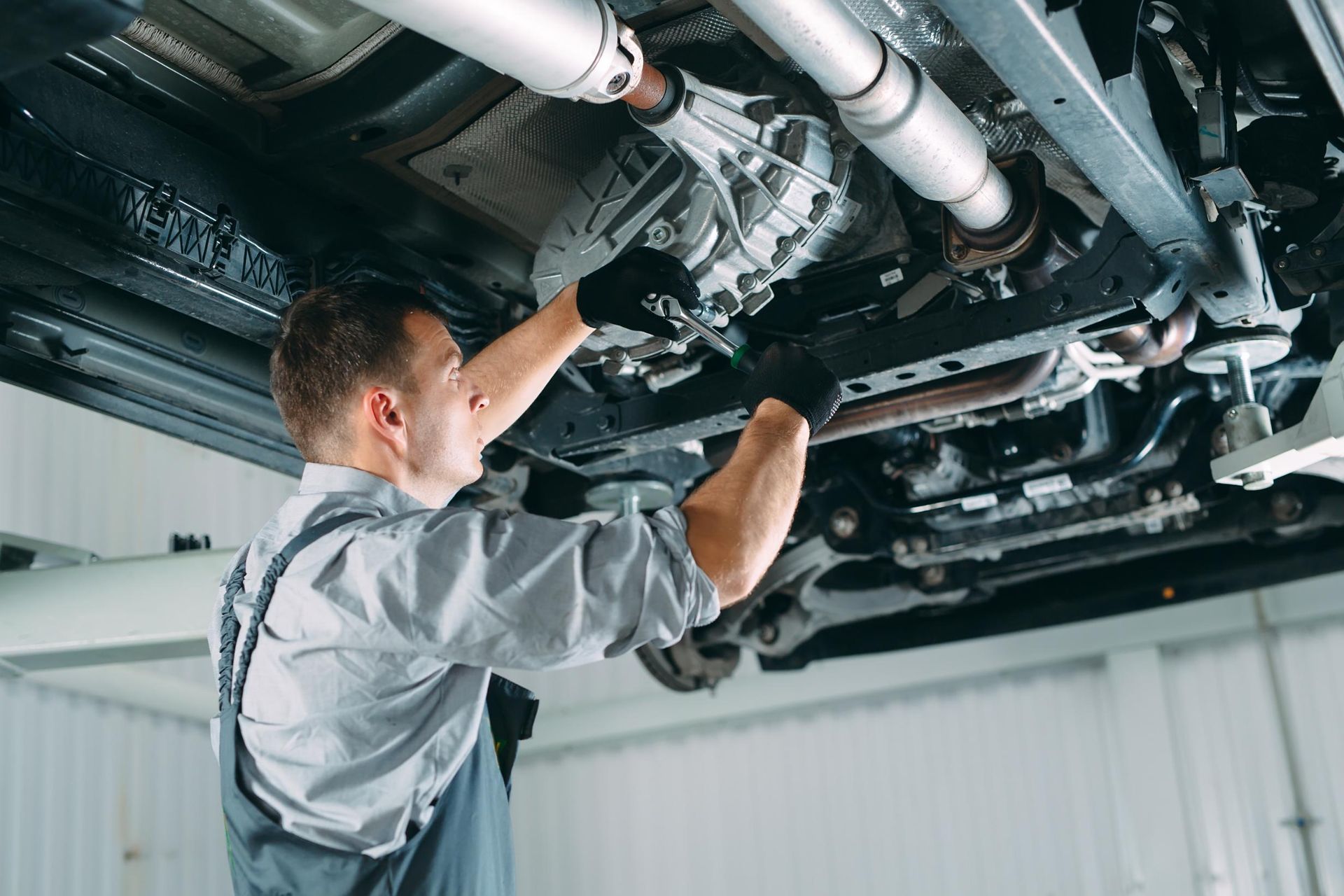 Mechanic inspecting the underside of a car on a lift in an auto repair shop