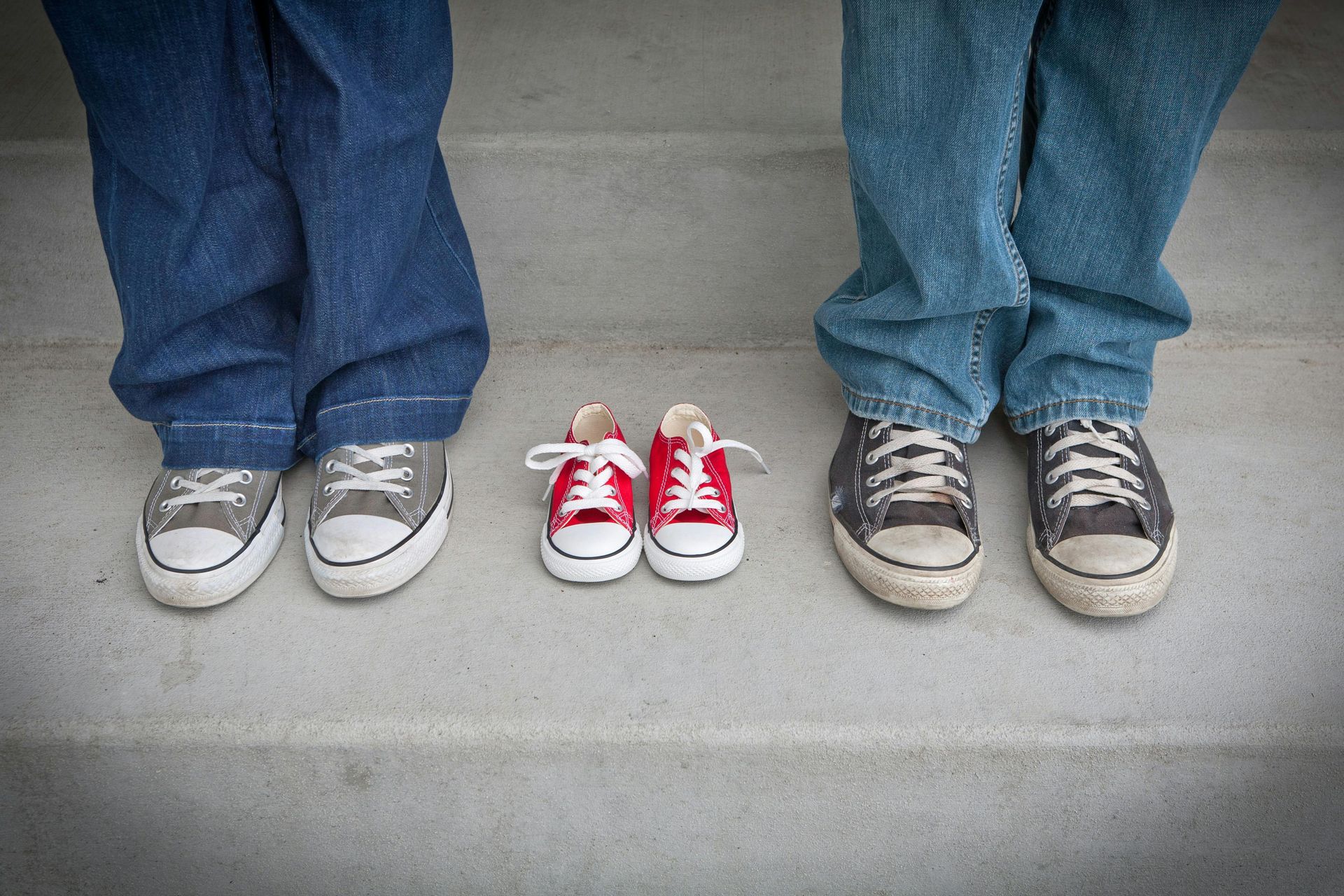 A couple of people standing next to each other wearing converse shoes