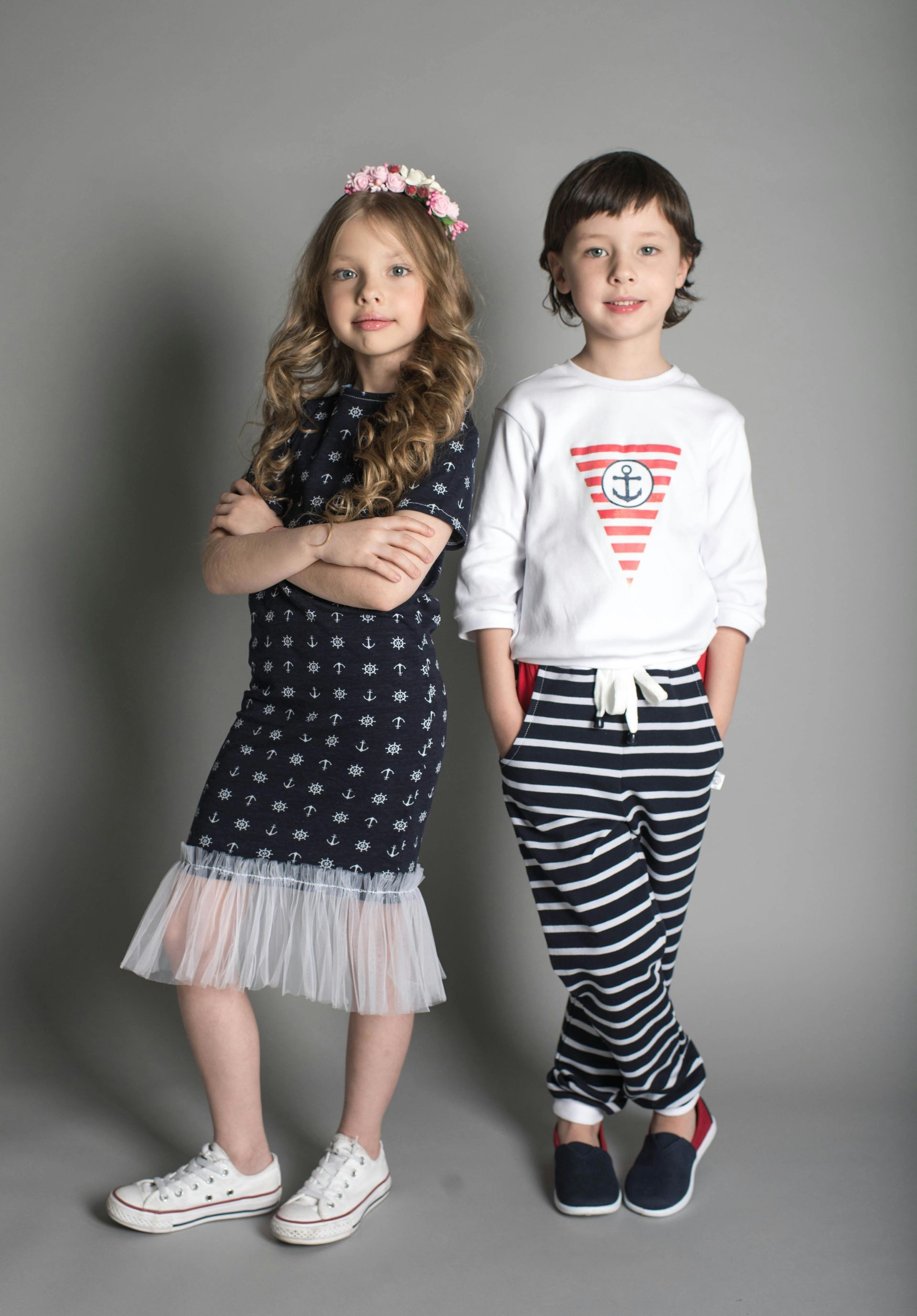 A boy and a girl are standing next to each other with their arms crossed.