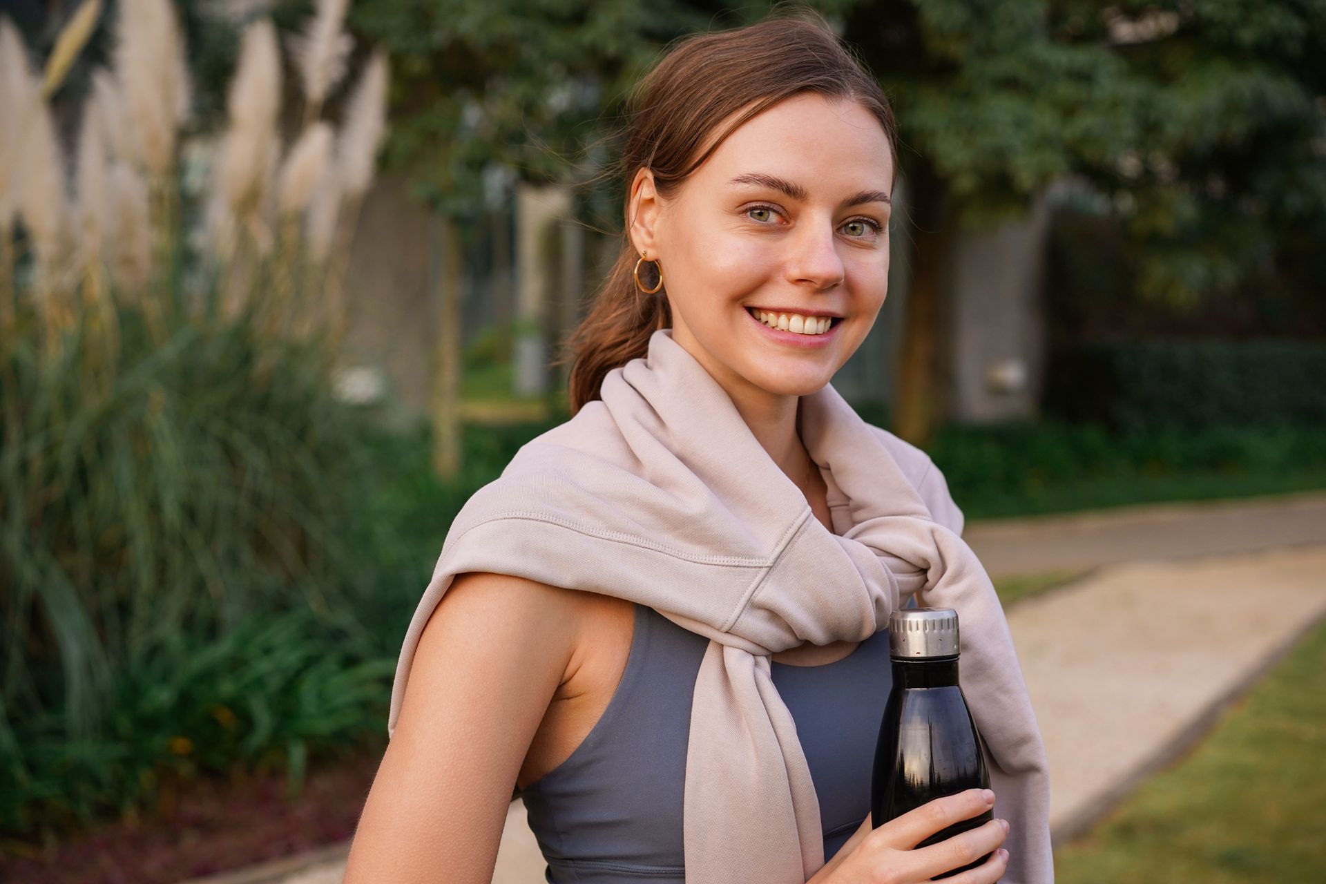 A woman is holding a bottle of water and smiling.