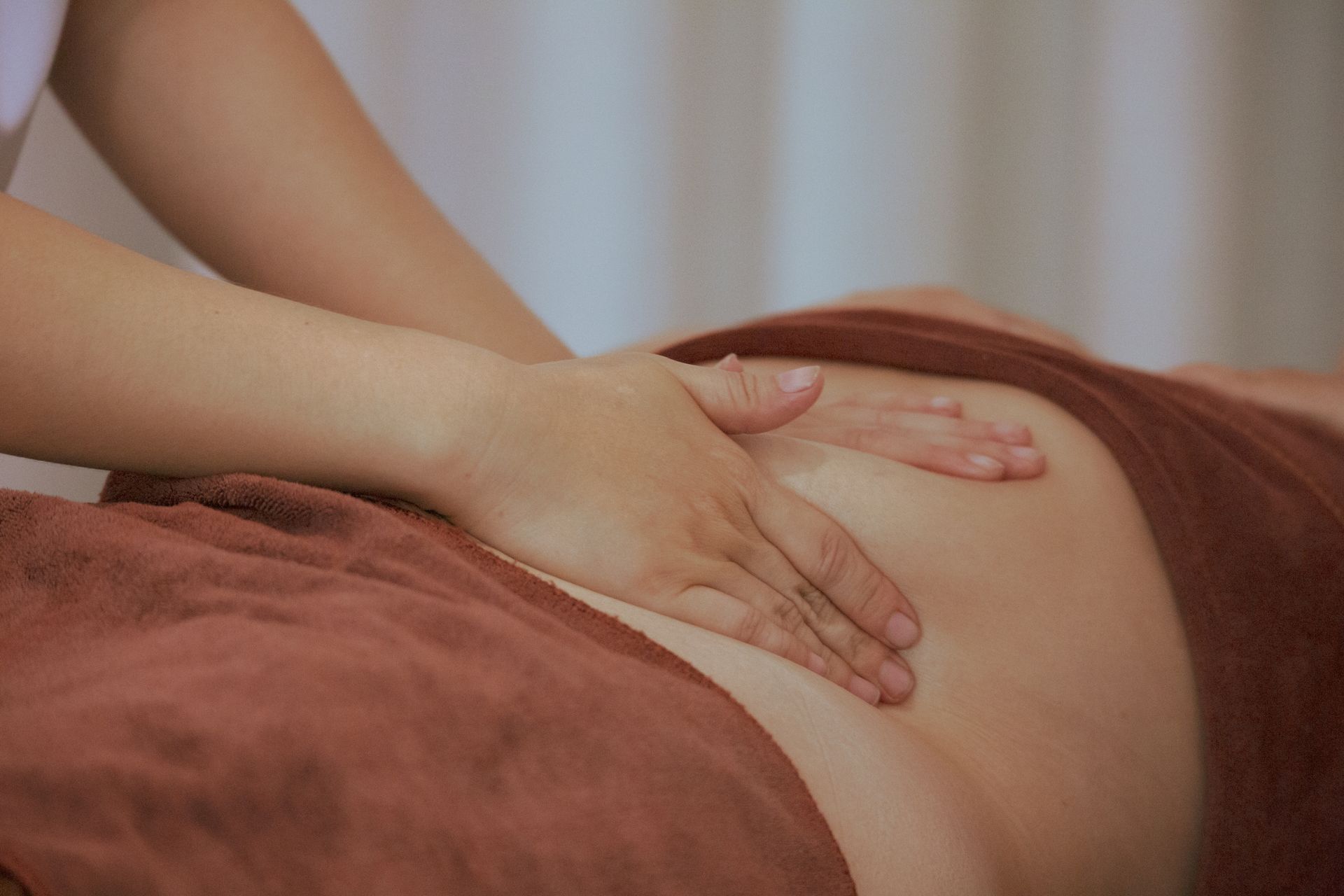 Hands massaging a person's leg. Focused on calf with the leg lying on a blue towel.