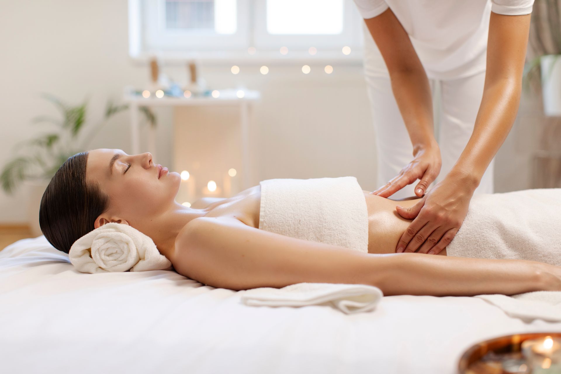 Spa therapist giving a back massage to a client on a treatment table