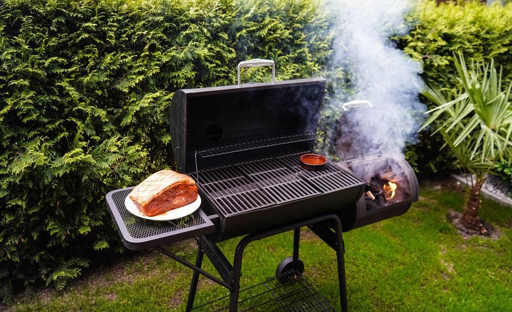 Barbecue Grill With Food Smoking on a Grassy Lawn — AB QUICK Painting & Maintenance Services In Mareeba, QLD