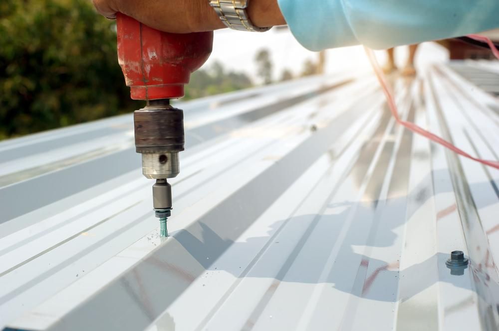 Person Using a Red Drill to Install a Metal Roof, Outdoors — AB QUICK Painting & Maintenance Services In Mareeba, QLD