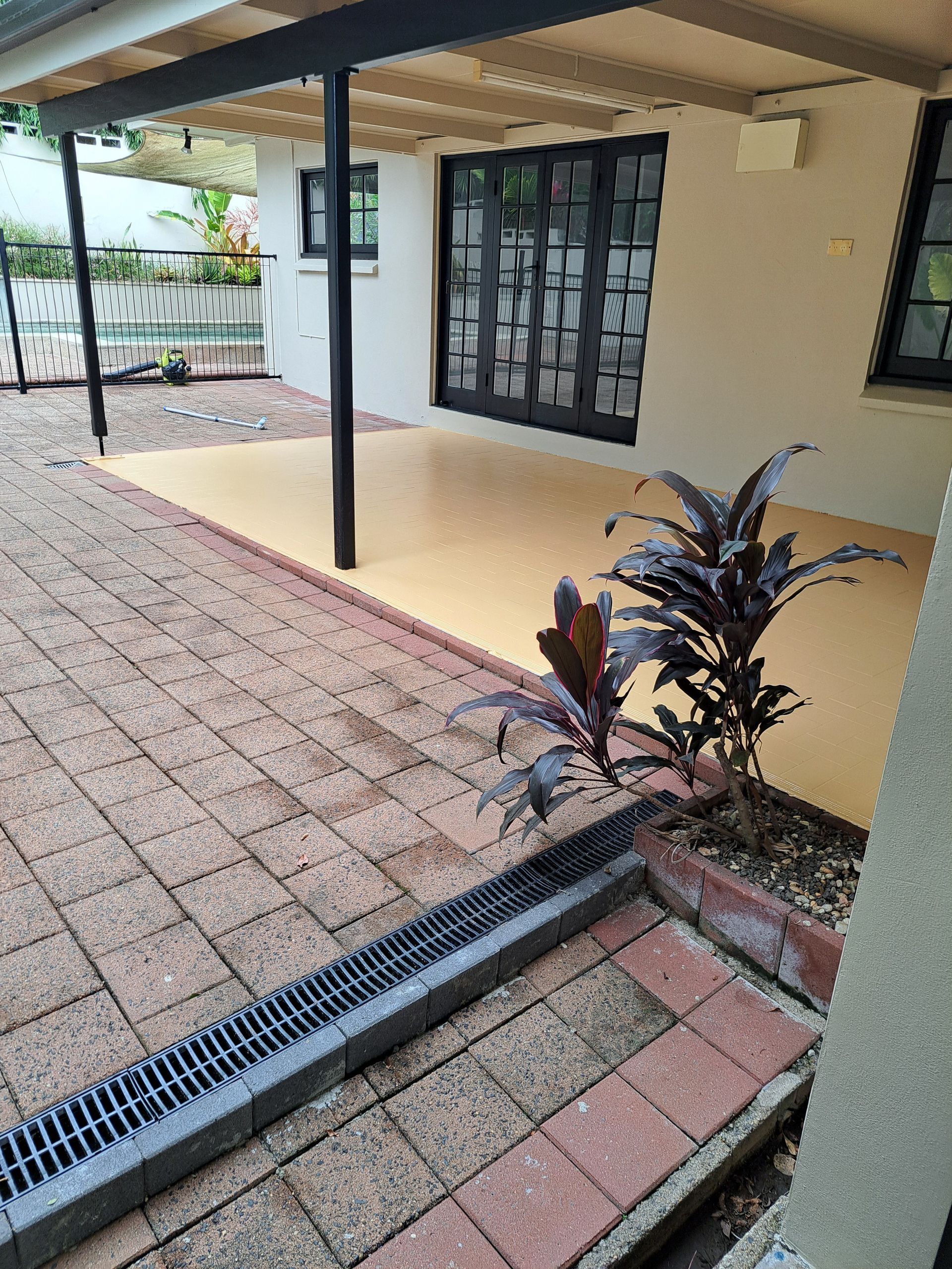 Patio with brick and concrete flooring, pergola, and plants. A French door is visible.