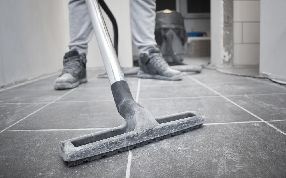 Person Vacuuming Gray Tiled Floor With a Gray Vacuum Cleaner — AB QUICK Painting & Maintenance Services In Mareeba, QLD