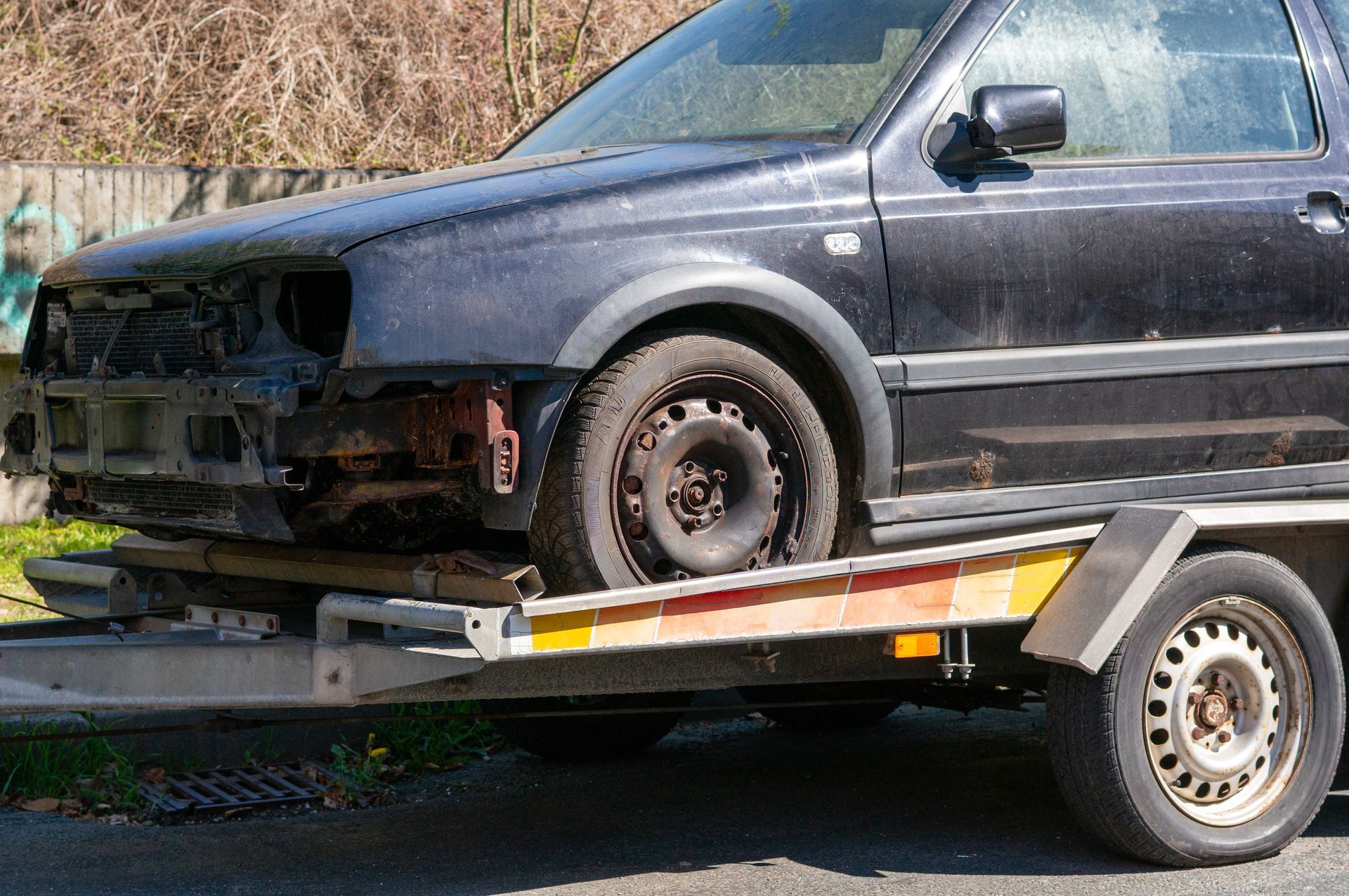 Damaged black SUV strapped on a tow trailer outdoors