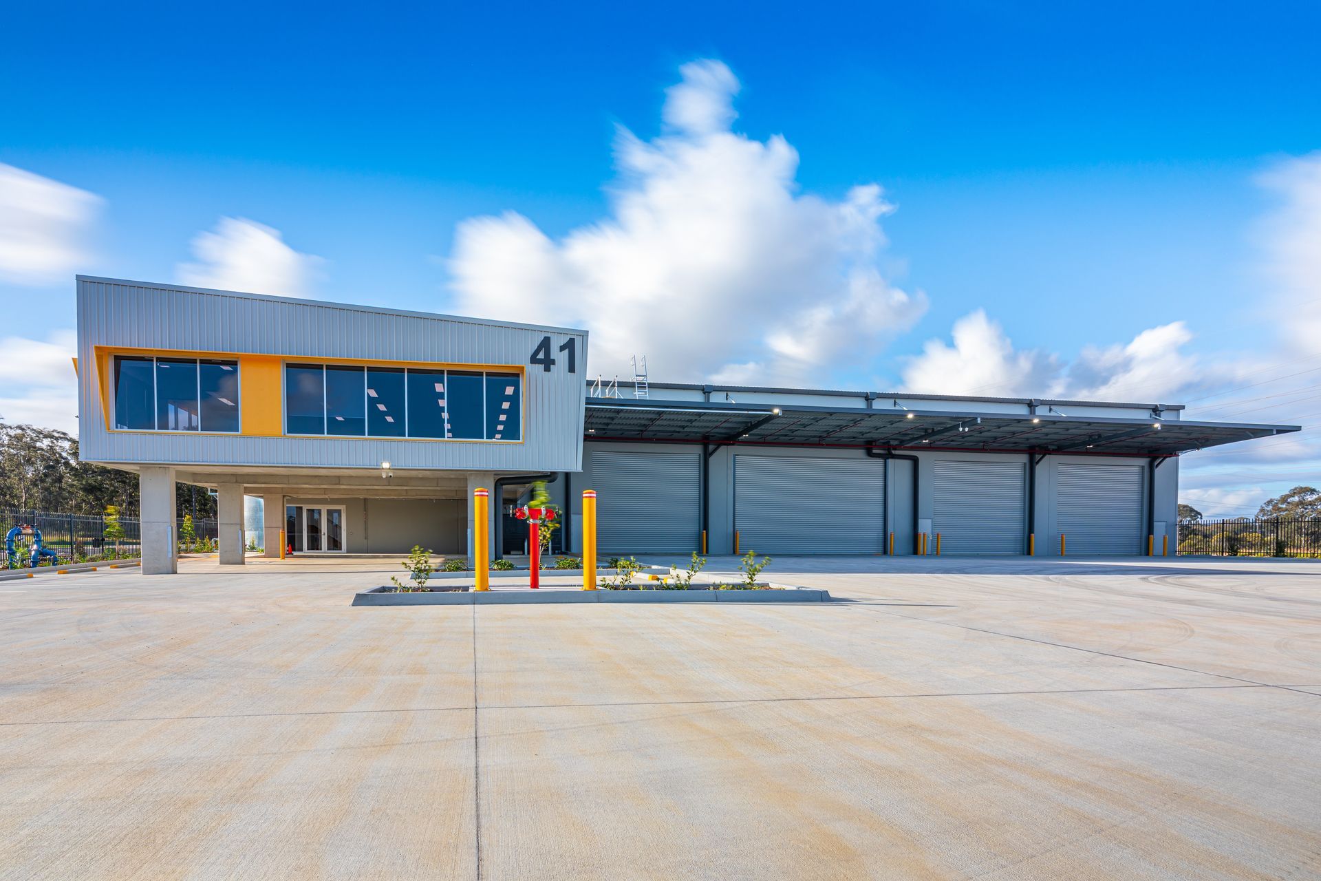 Modern bus terminal with a glass-front building and covered platform under a bright blue sky