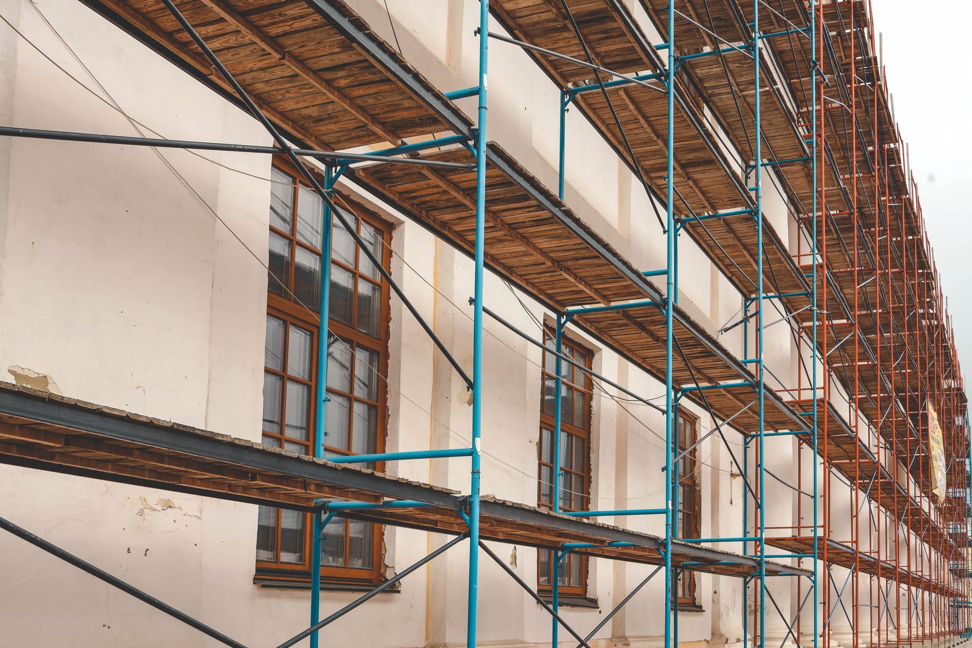Scaffolding along a building facade with blue support poles and wooden platforms under construction