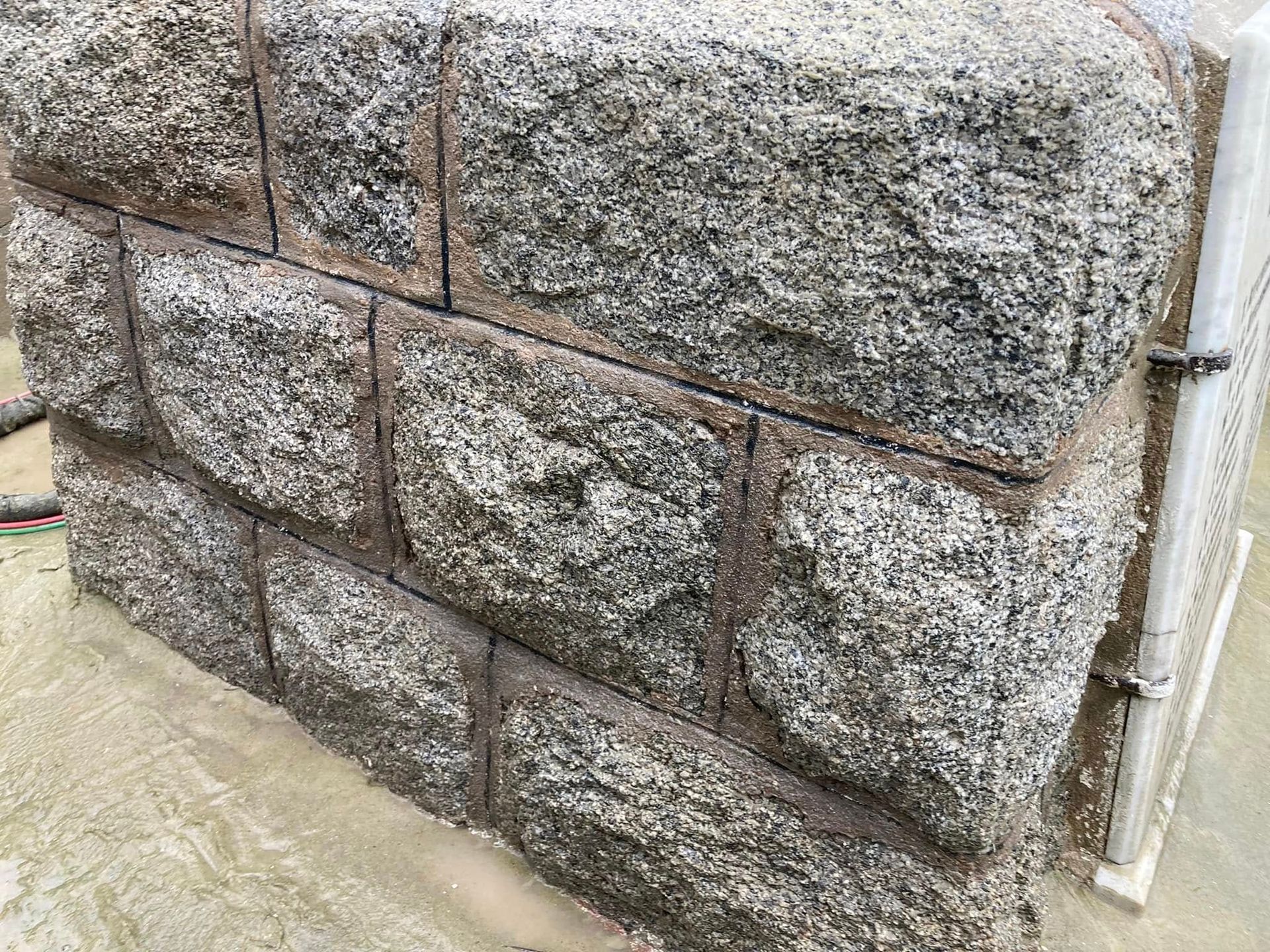 Close-up of a rough gray stone wall with mortar joints and a white pipe on the right side Close-up of a rough gray stone wall with mortar joints and a white pipe on the right side