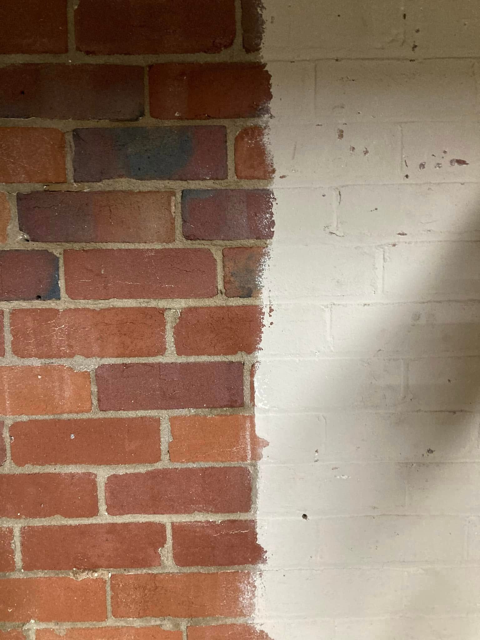 Half brick wall, half white plaster wall with a vertical seam between them.