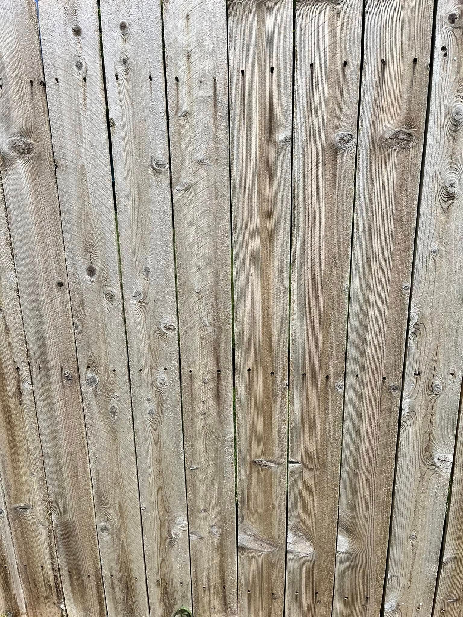 A close up of a wooden fence with holes in it.