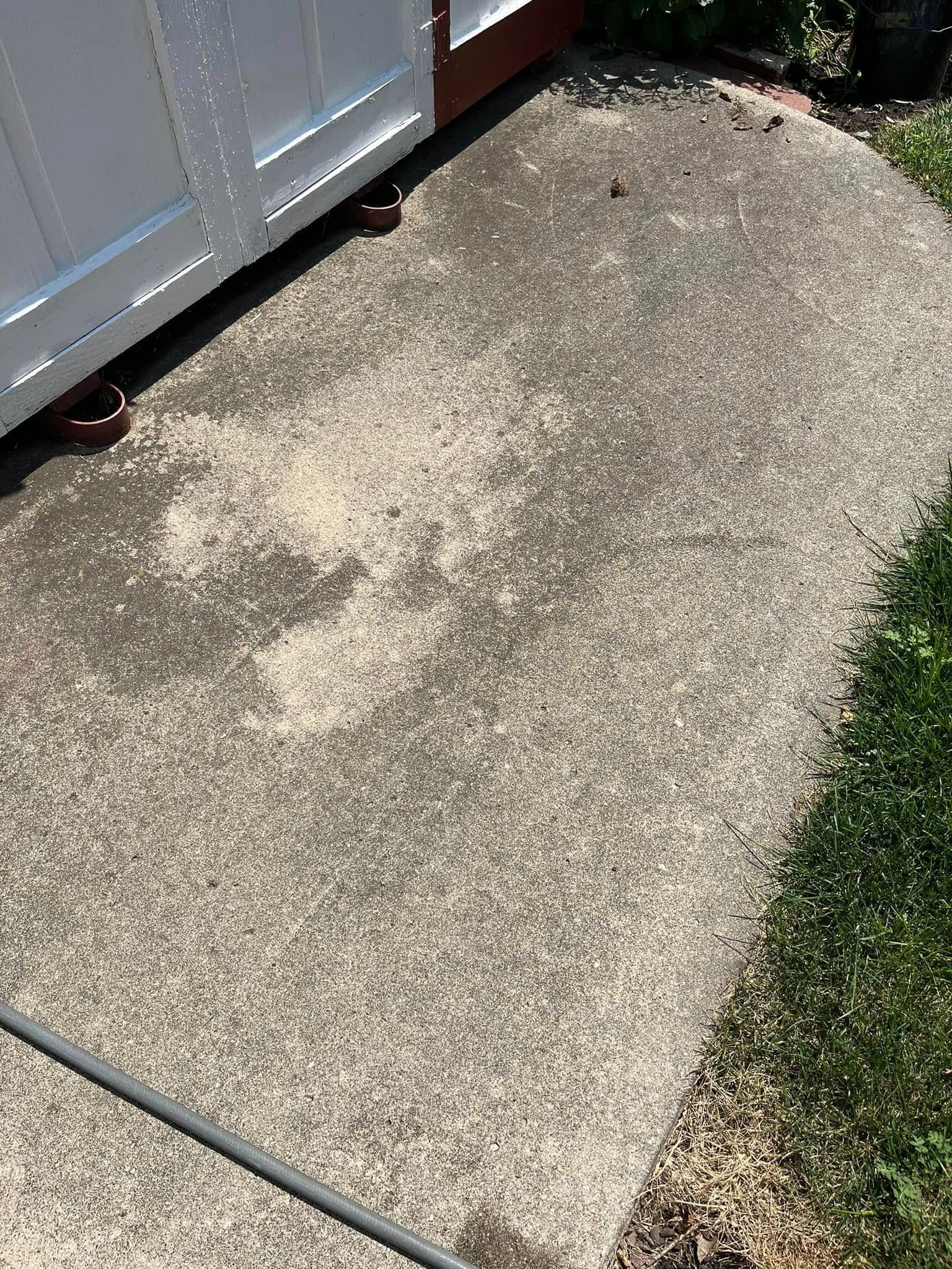 A concrete sidewalk next to a white garage door.