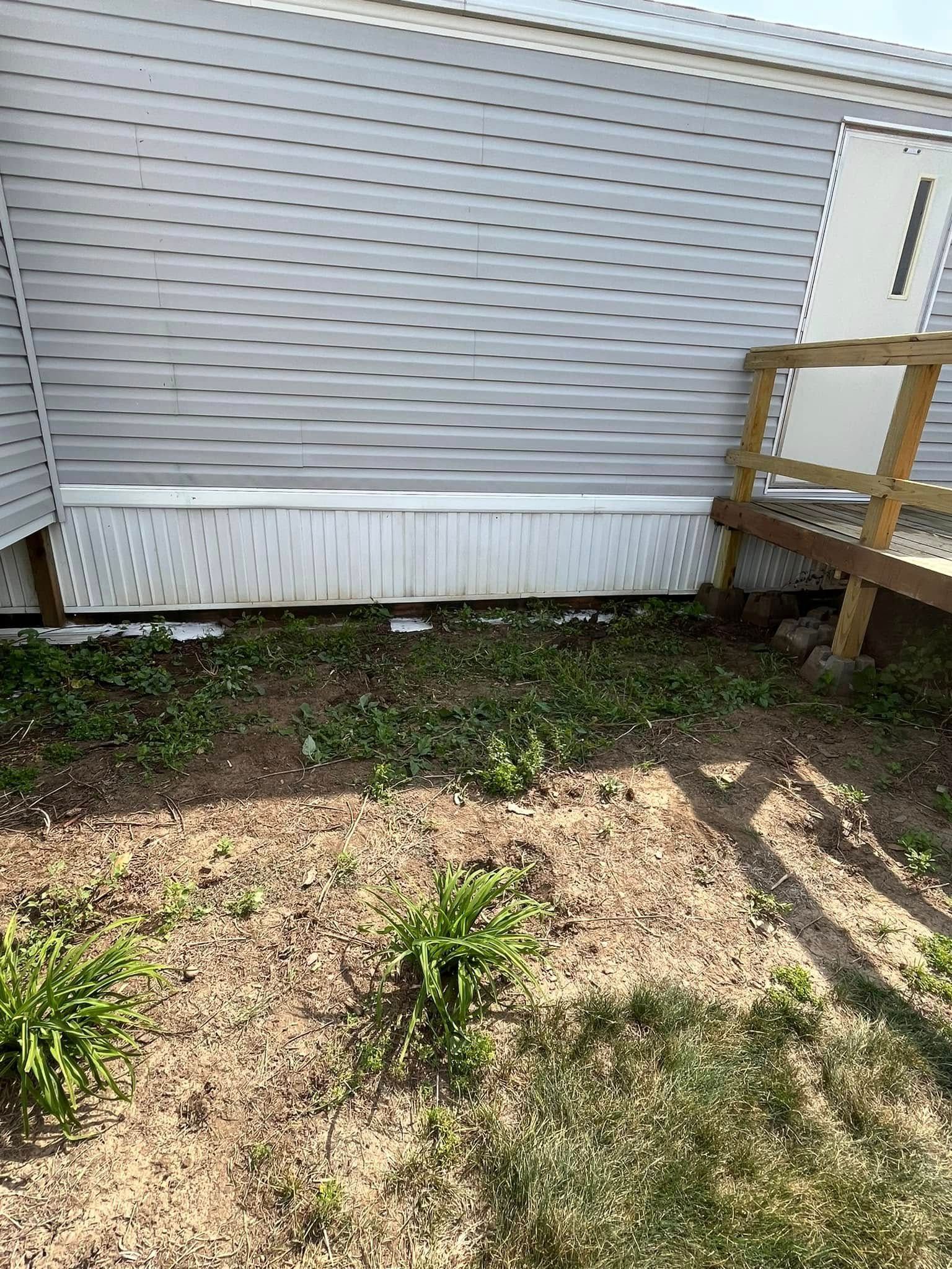 A white mobile home with a wooden deck in front of it.