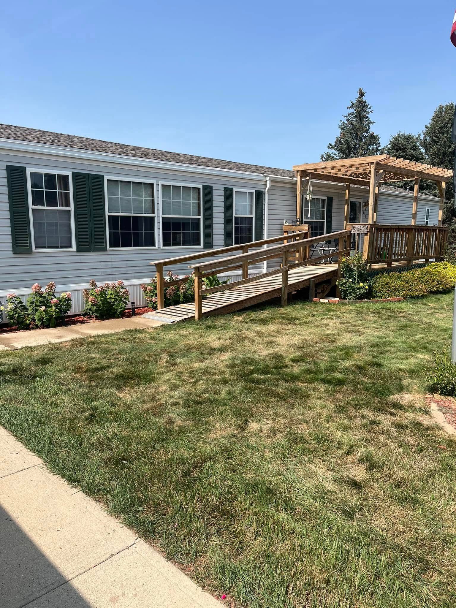 A mobile home with a ramp and a pergola in front of it.