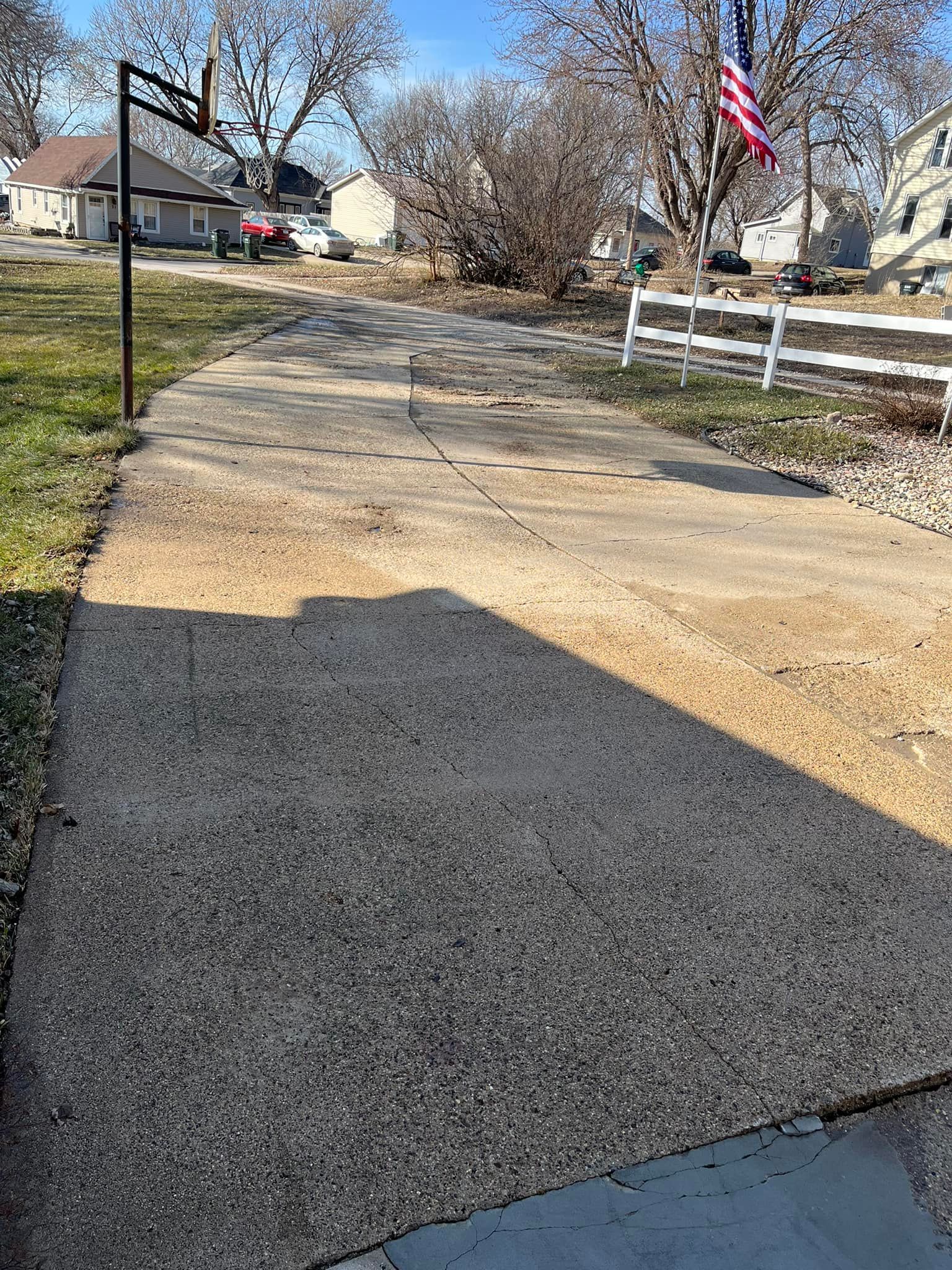 A concrete driveway leading to a house with a flag on the side of it.