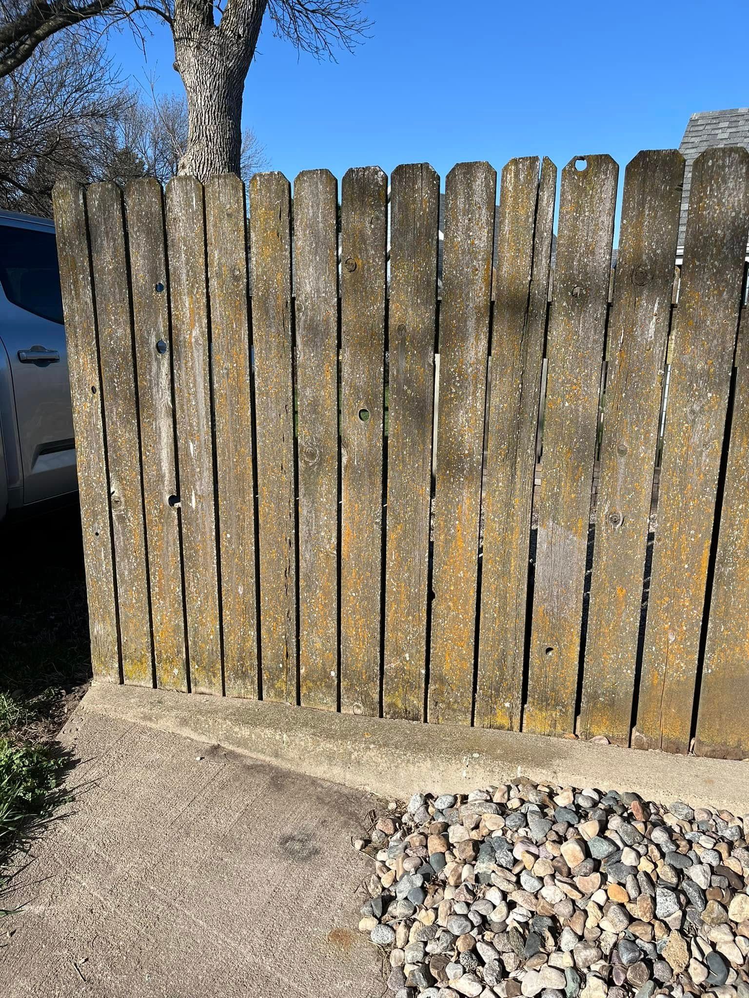 A wooden fence is sitting next to a pile of gravel.
