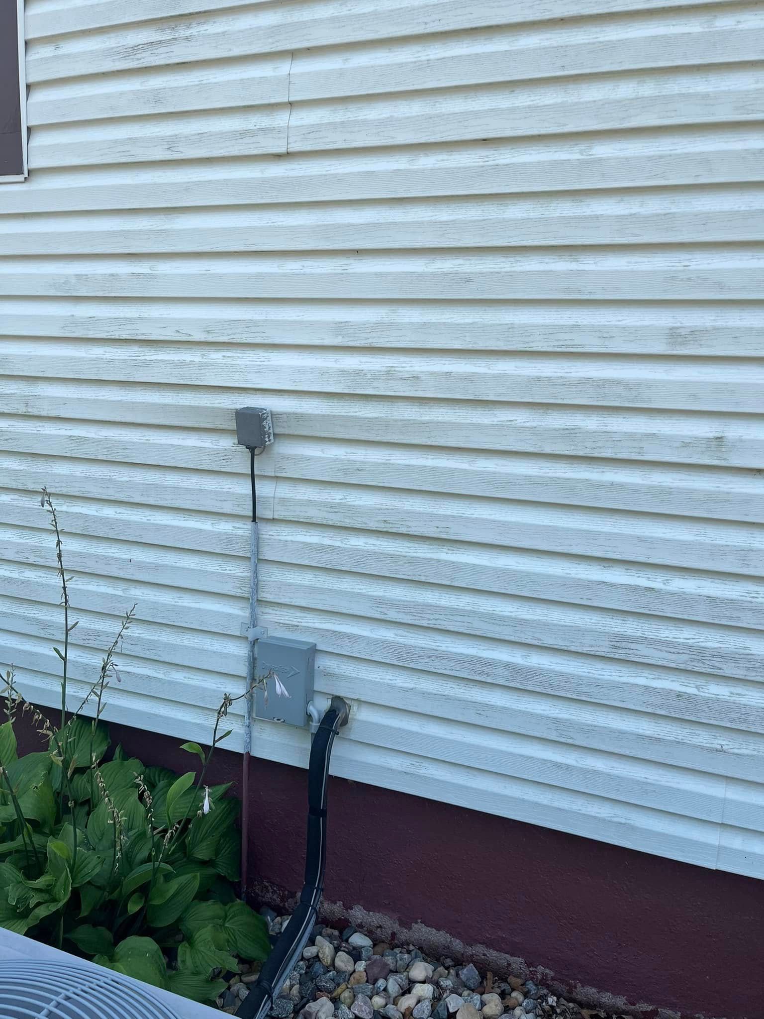 A white house with a electrical outlet on the side of it.