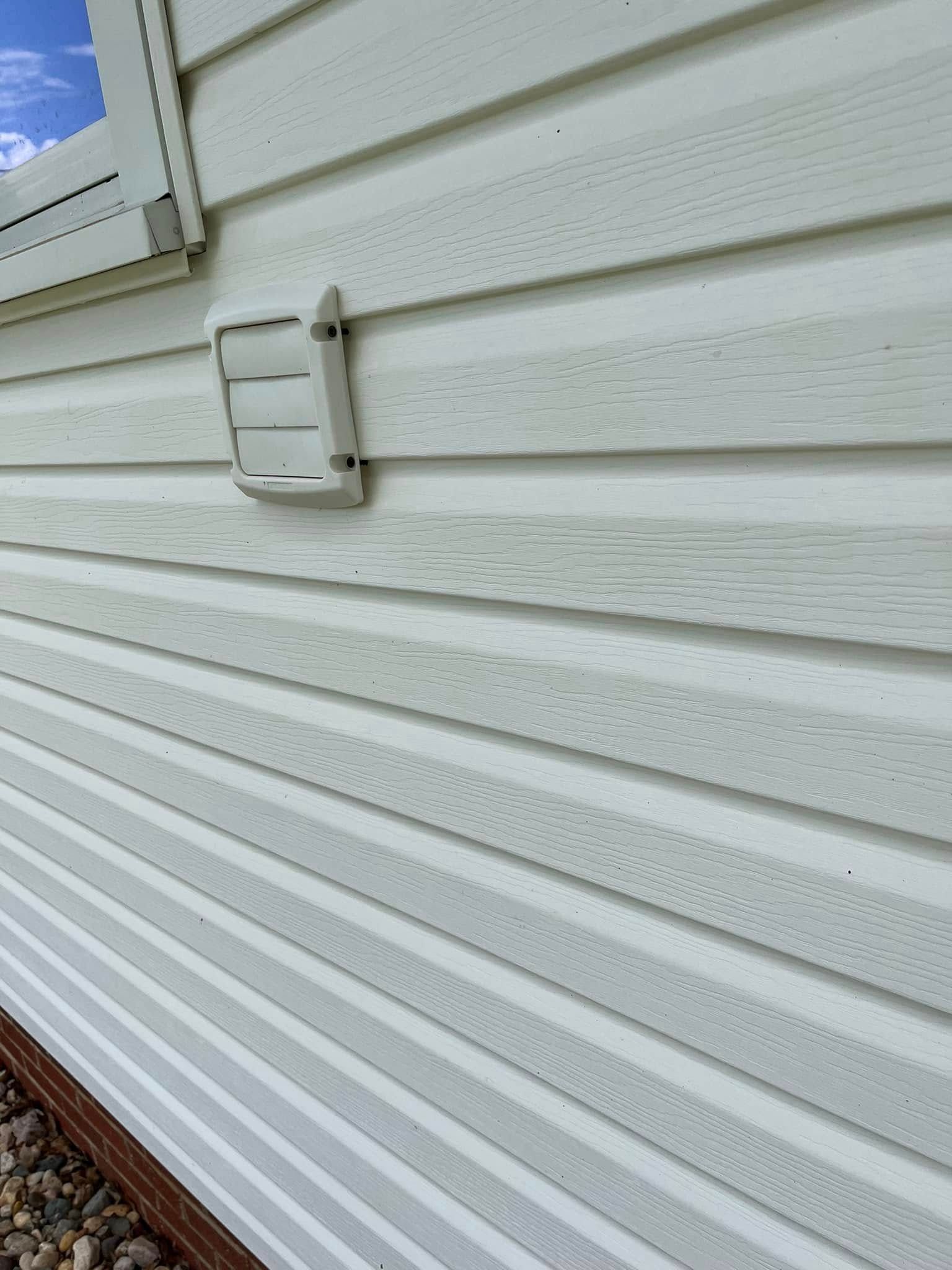 A close up of a white siding on a house with a window.