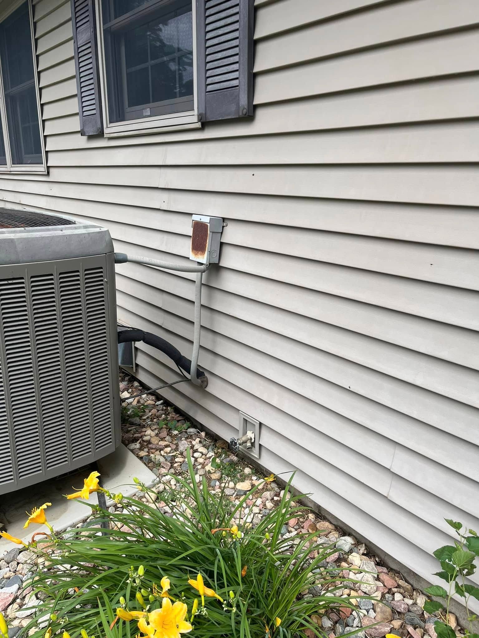 A house with a gray air conditioner on the side of it.