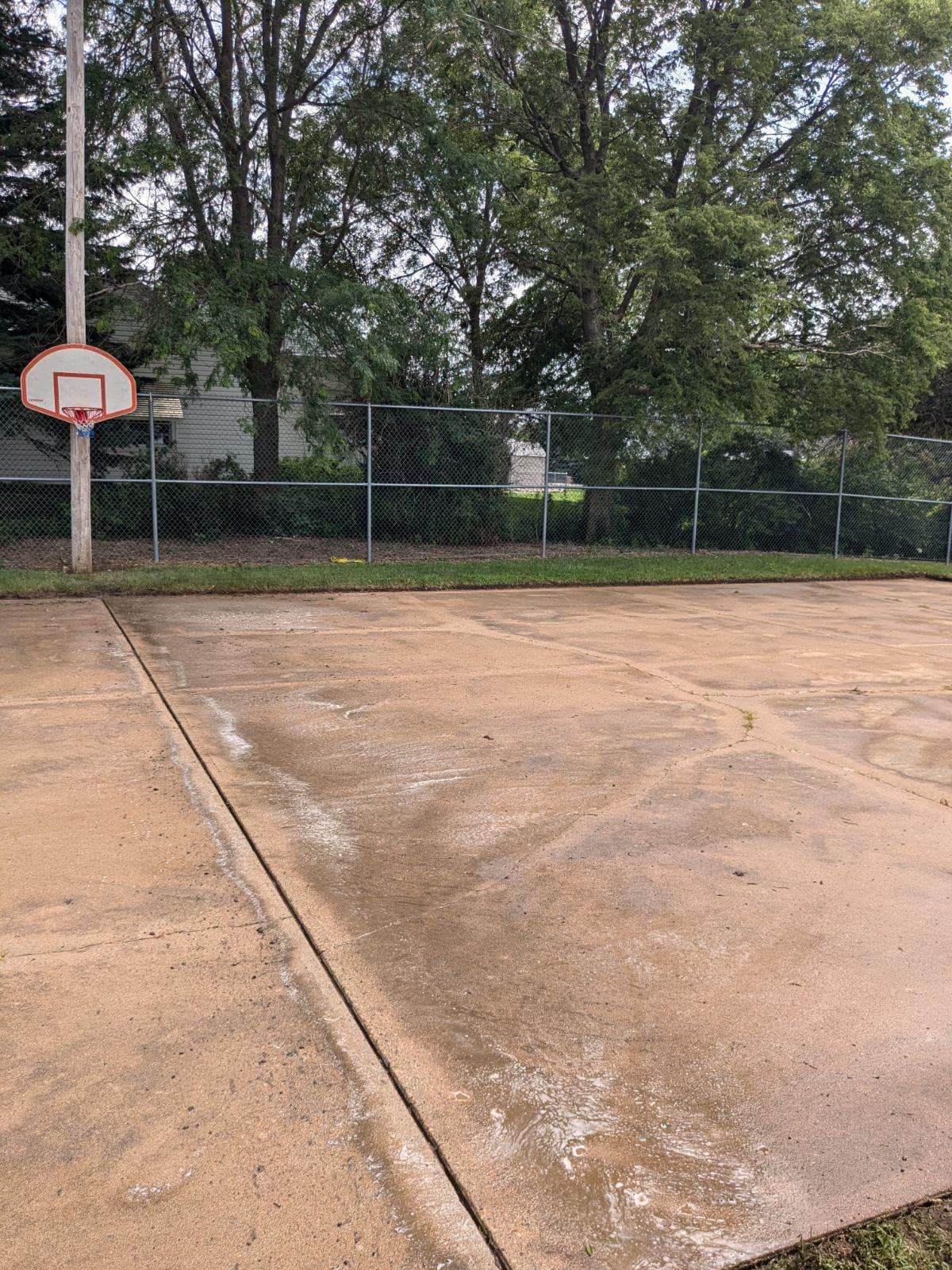 There is a basketball hoop in the middle of a concrete court.
