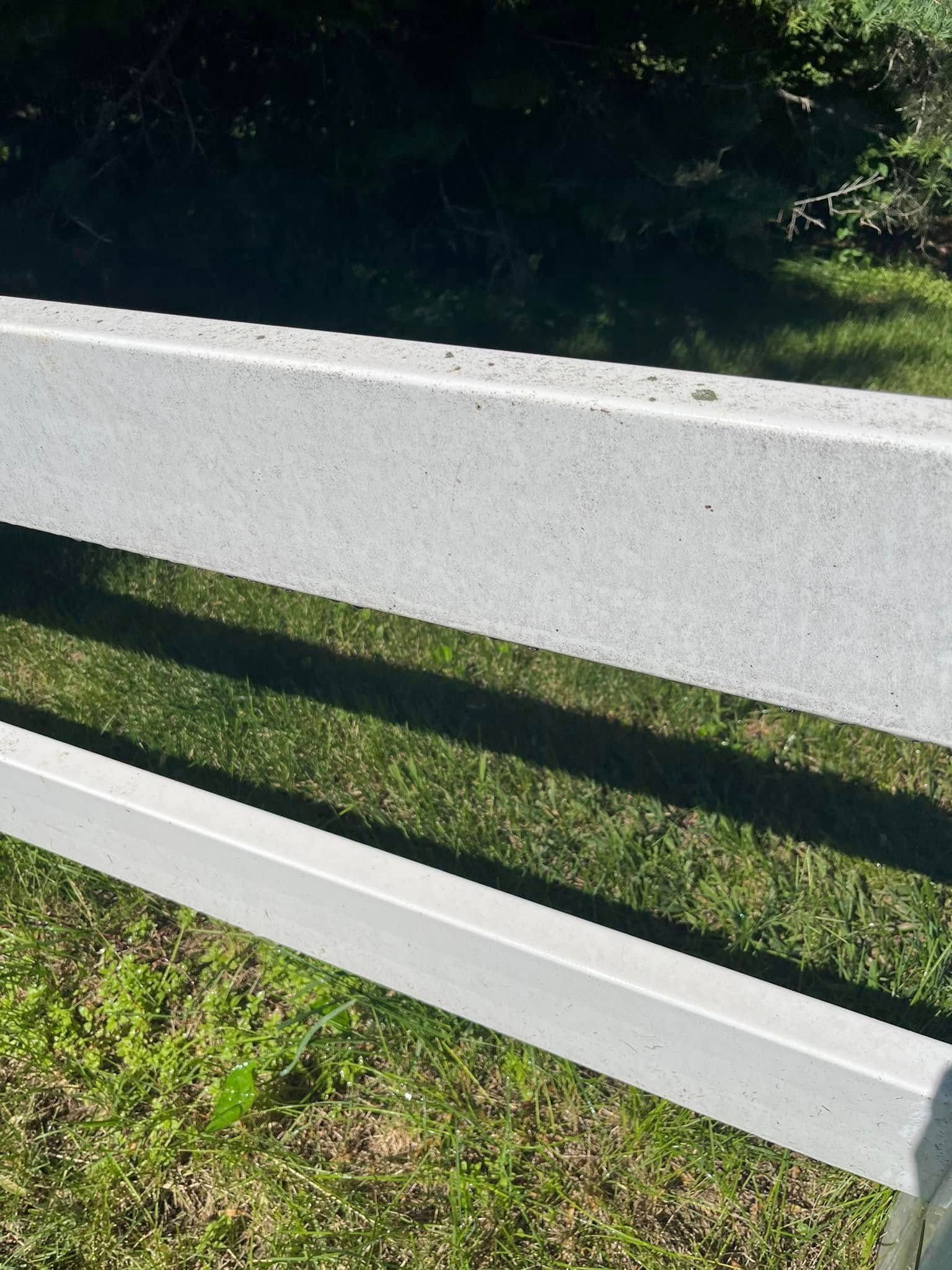 A white fence is sitting on top of a lush green field.