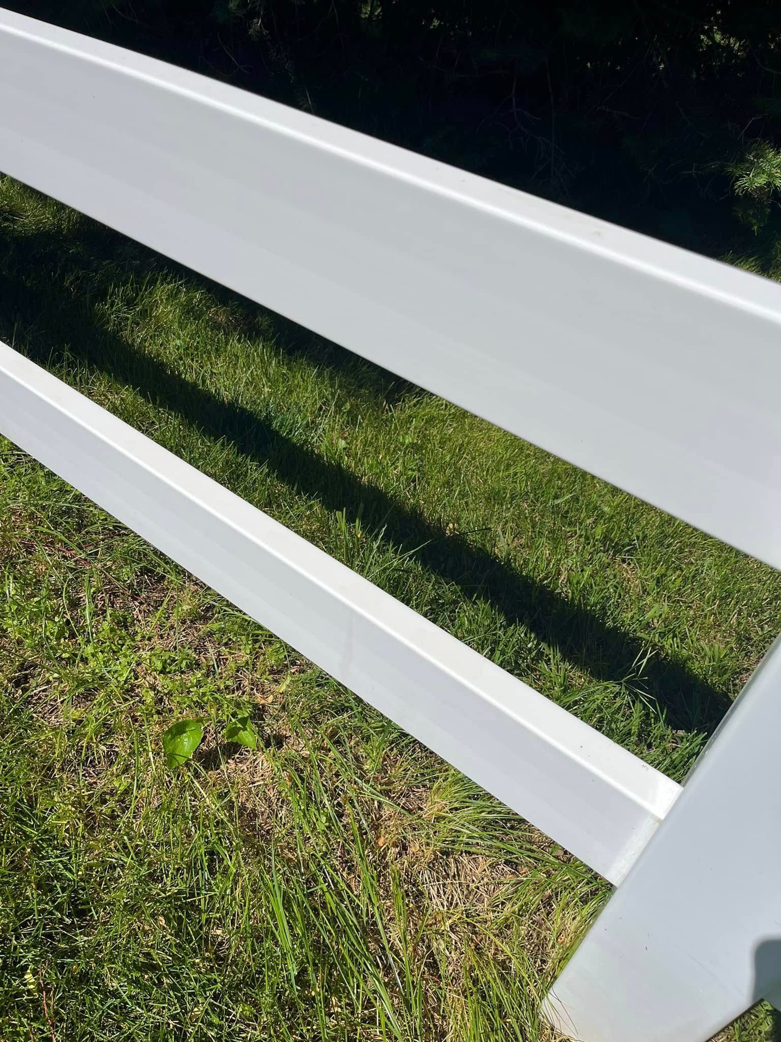 A white fence is sitting on top of a lush green field.