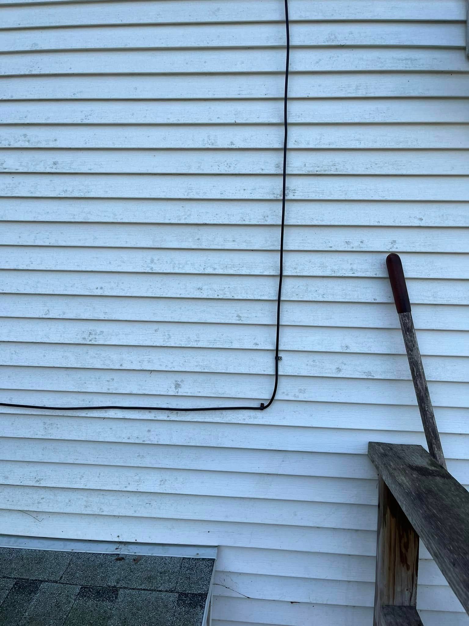 A white siding with a wire hanging off of it