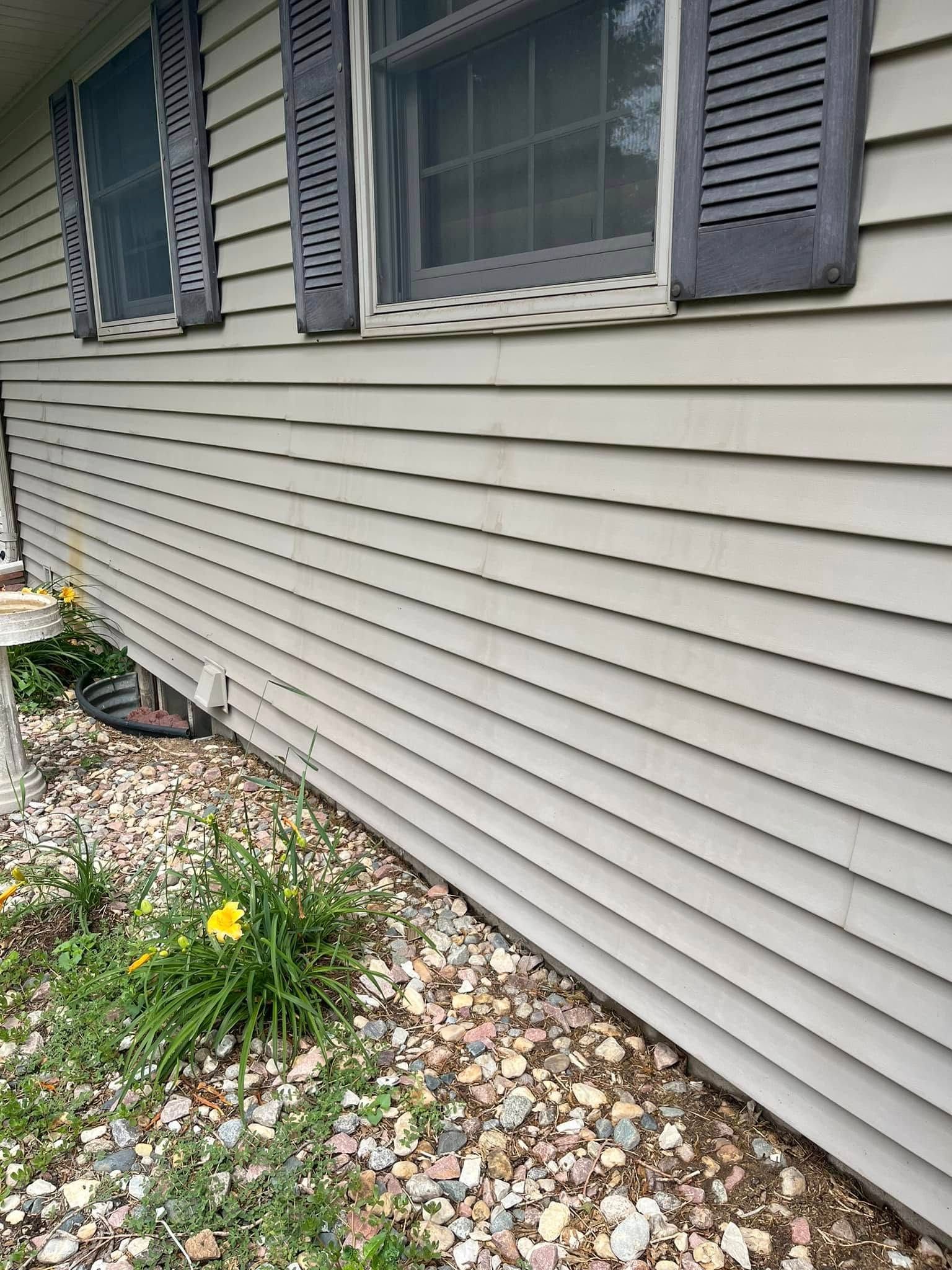 The side of a house with a lot of rocks and flowers in front of it.