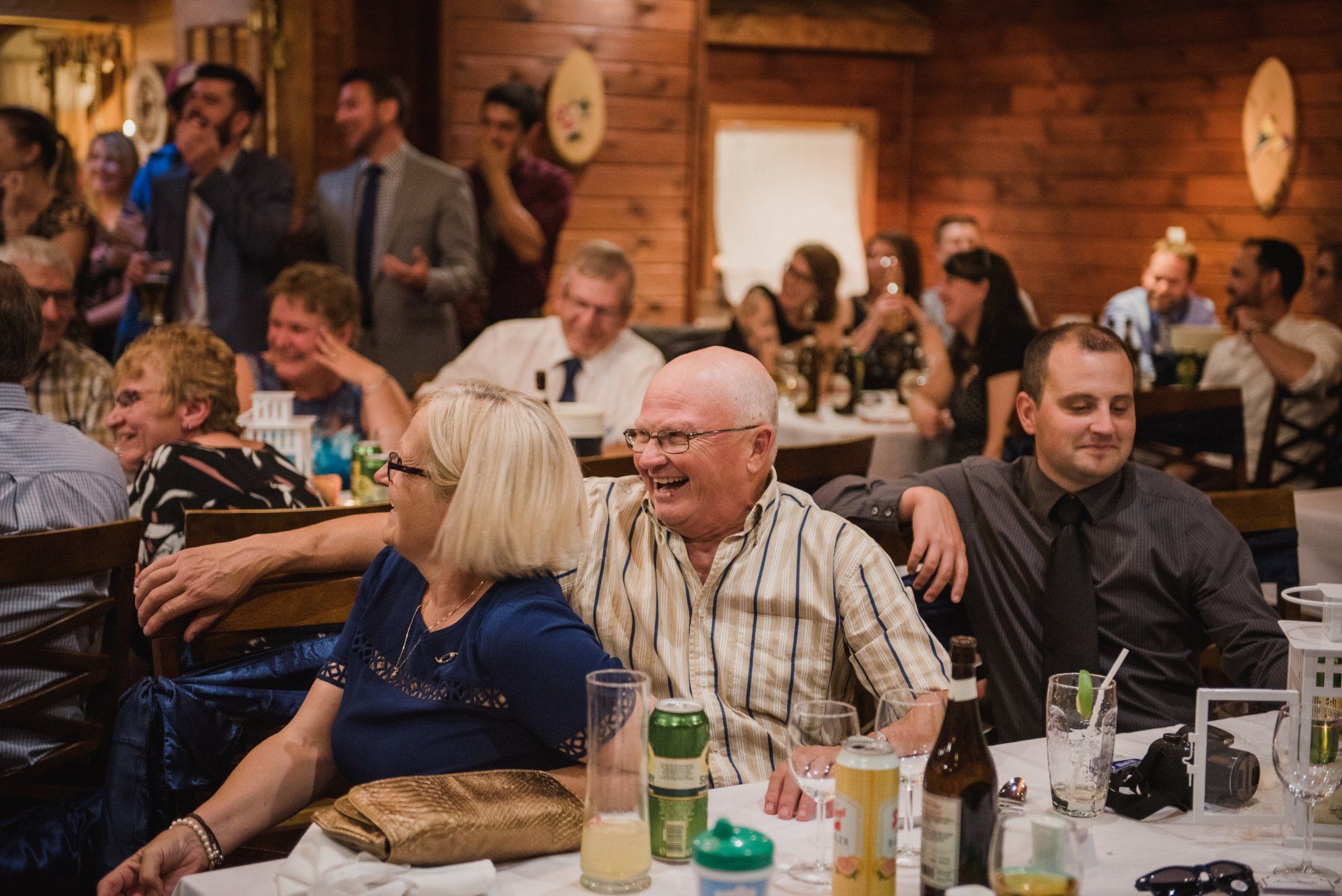Guests seated at tables in a warmly lit restaurant, chatting and drinking at a social gathering