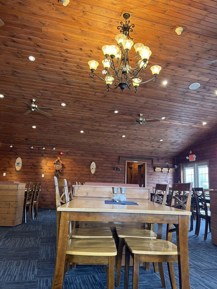 Rustic restaurant dining room with wooden tables, chandelier, and brick walls