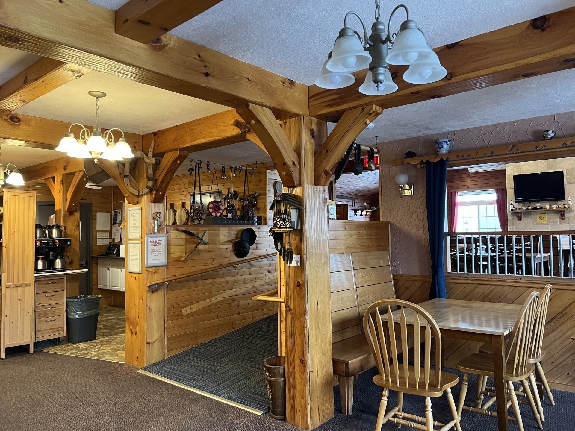 Rustic restaurant interior with wooden beams, bar, tables, and chairs under warm lighting